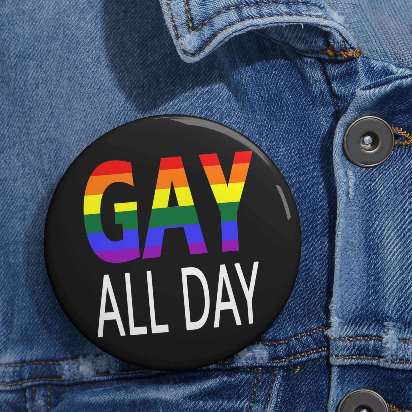 Black pin-back button that says Gay all day in rainbow font.