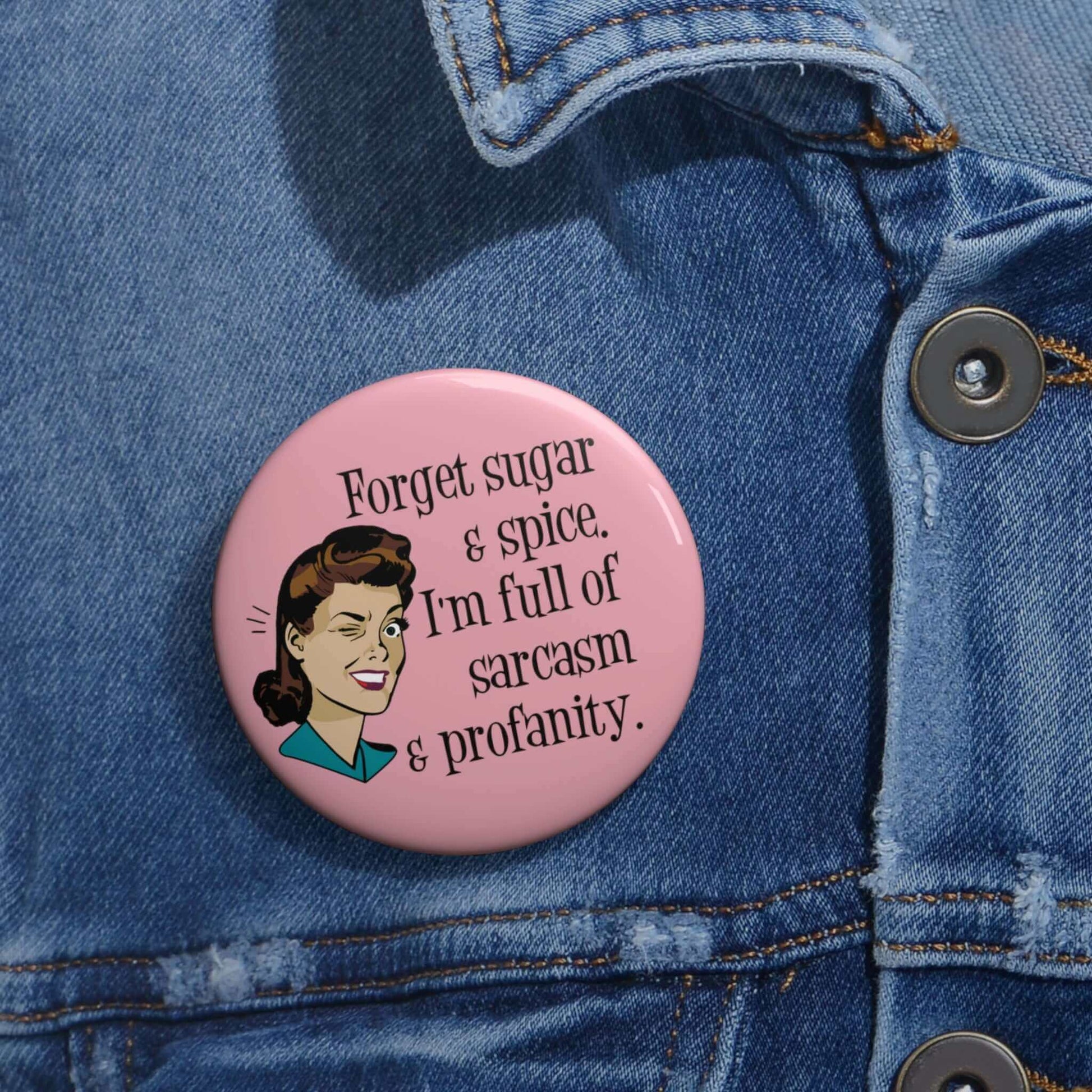 Pink pin-back button with image of winking retro woman and the words Forget sugar and spice, I'm full of sarcasm and profanity.