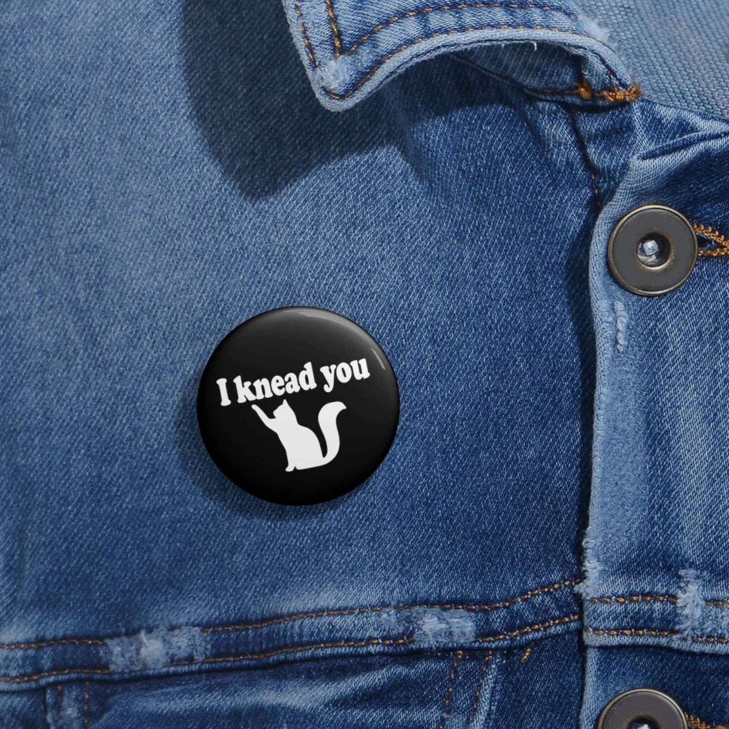 Pin-back button with silhouette of a cat and the words I knead you.