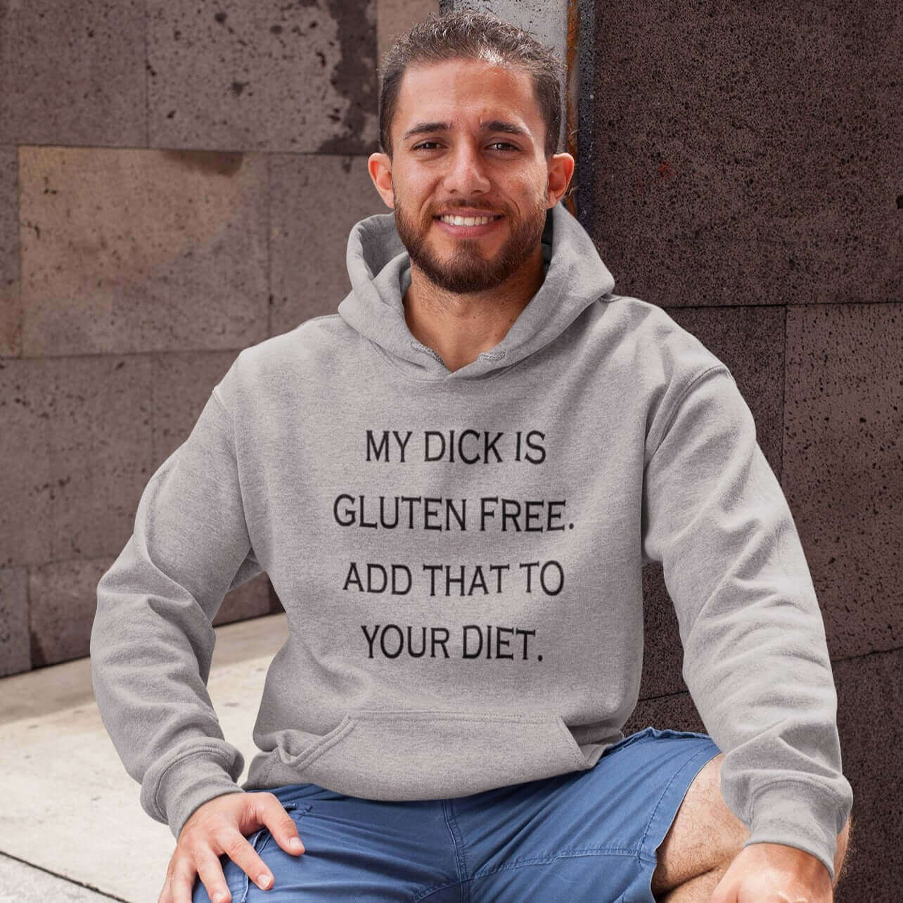 Man wearing a light grey hoodie sweatshirt with the funny phrase My dick is gluten free, add that to your diet printed on the front.