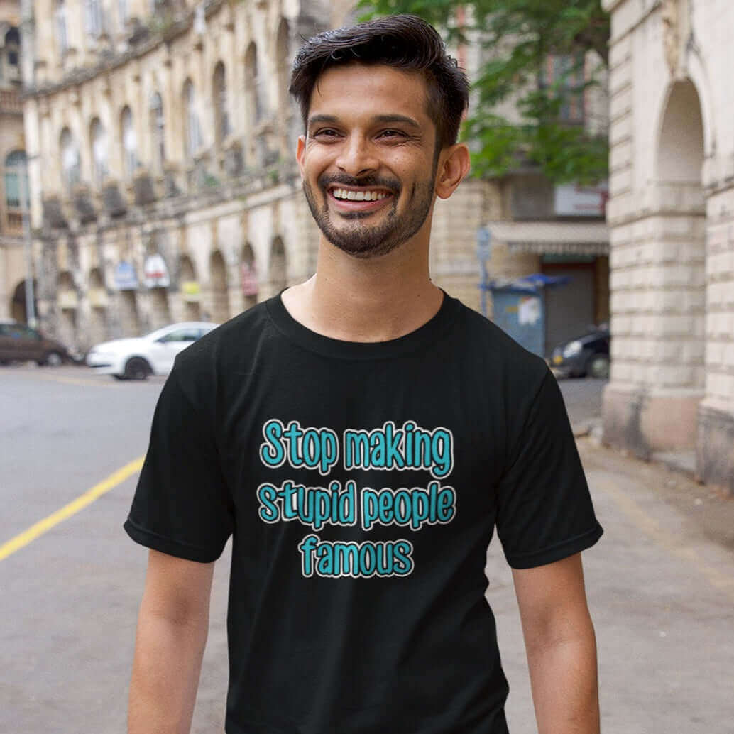 Man wearing black t-shirt with the phrase Stop making stupid people famous printed on the front. The text is turquoise. 