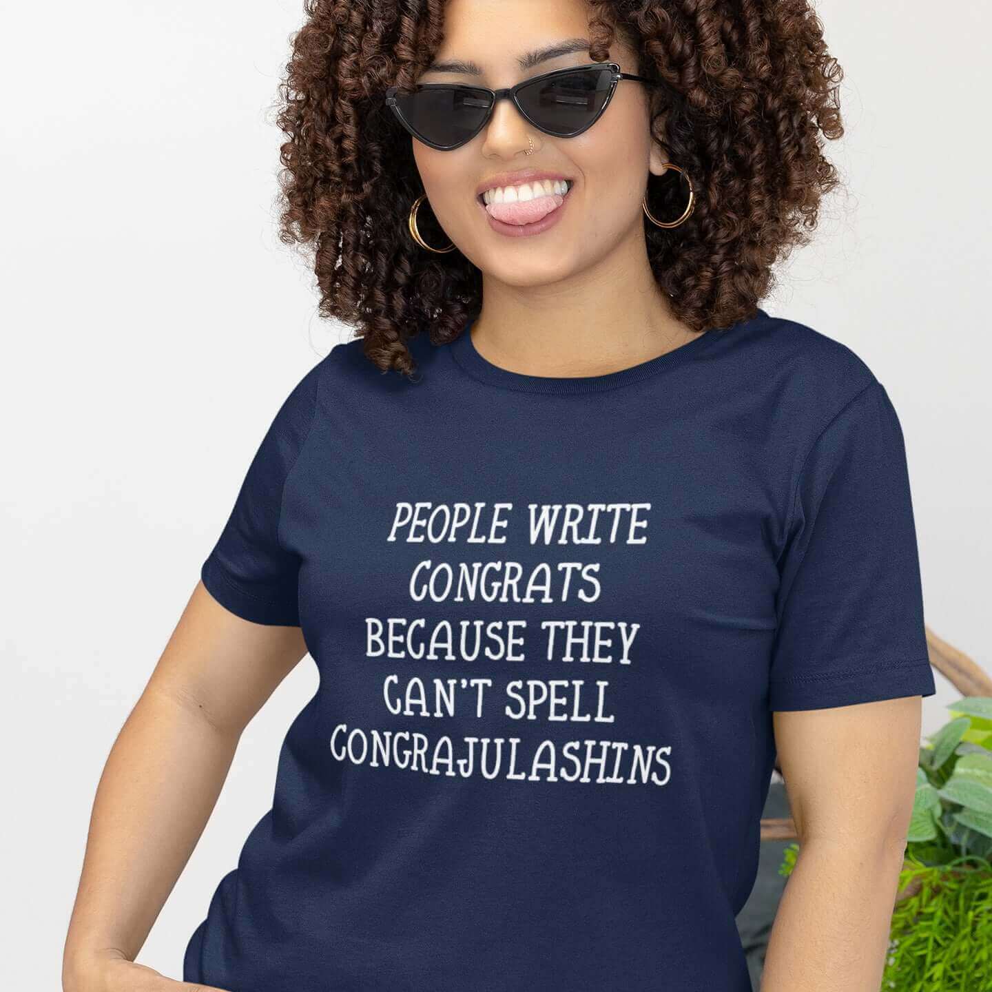 Woman wearing navy blue t-shirt with the words People write congrats because they can't spell congratulations printed on the front. The word congratulations is intentionally misspelled.