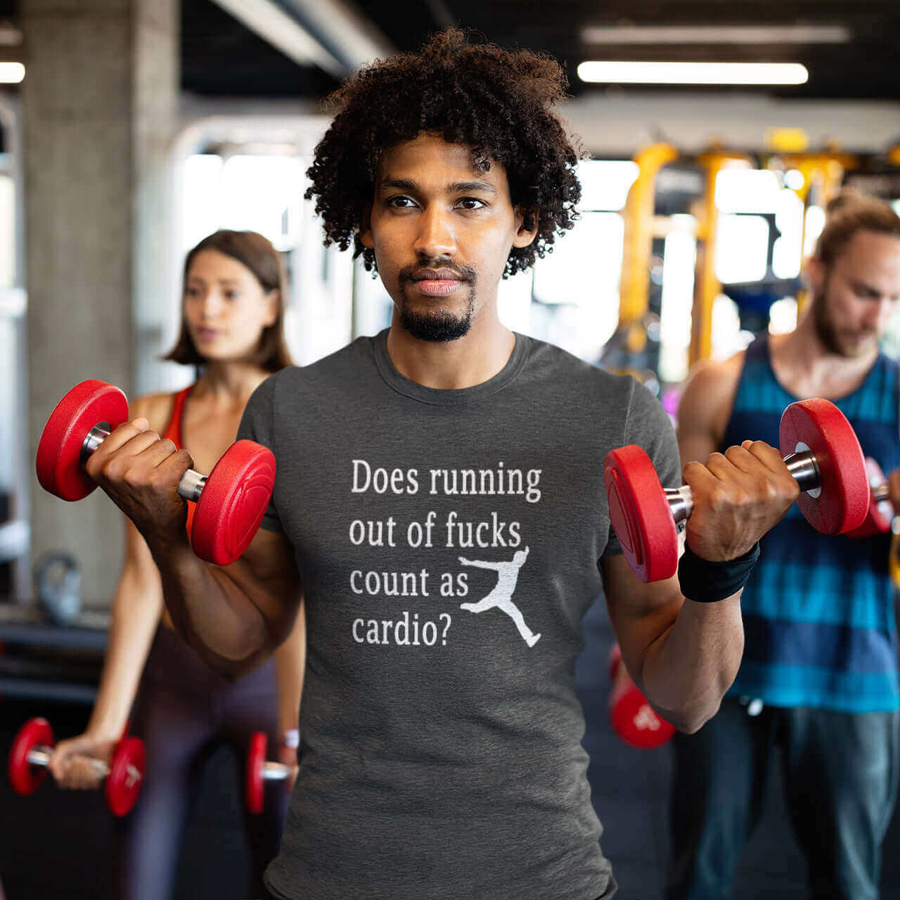 Man in a gym wearing a dark heather t-shirt with a silhouette image of a running person with the phrase Does running out of fucks count as cardio question mark printed on the front.