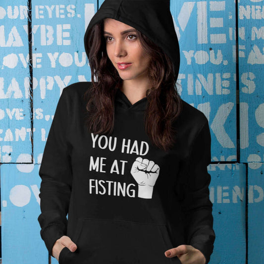 Woman wearing black hooded sweatshirt with image of a fist and the words You had me at fisting printed on the front.