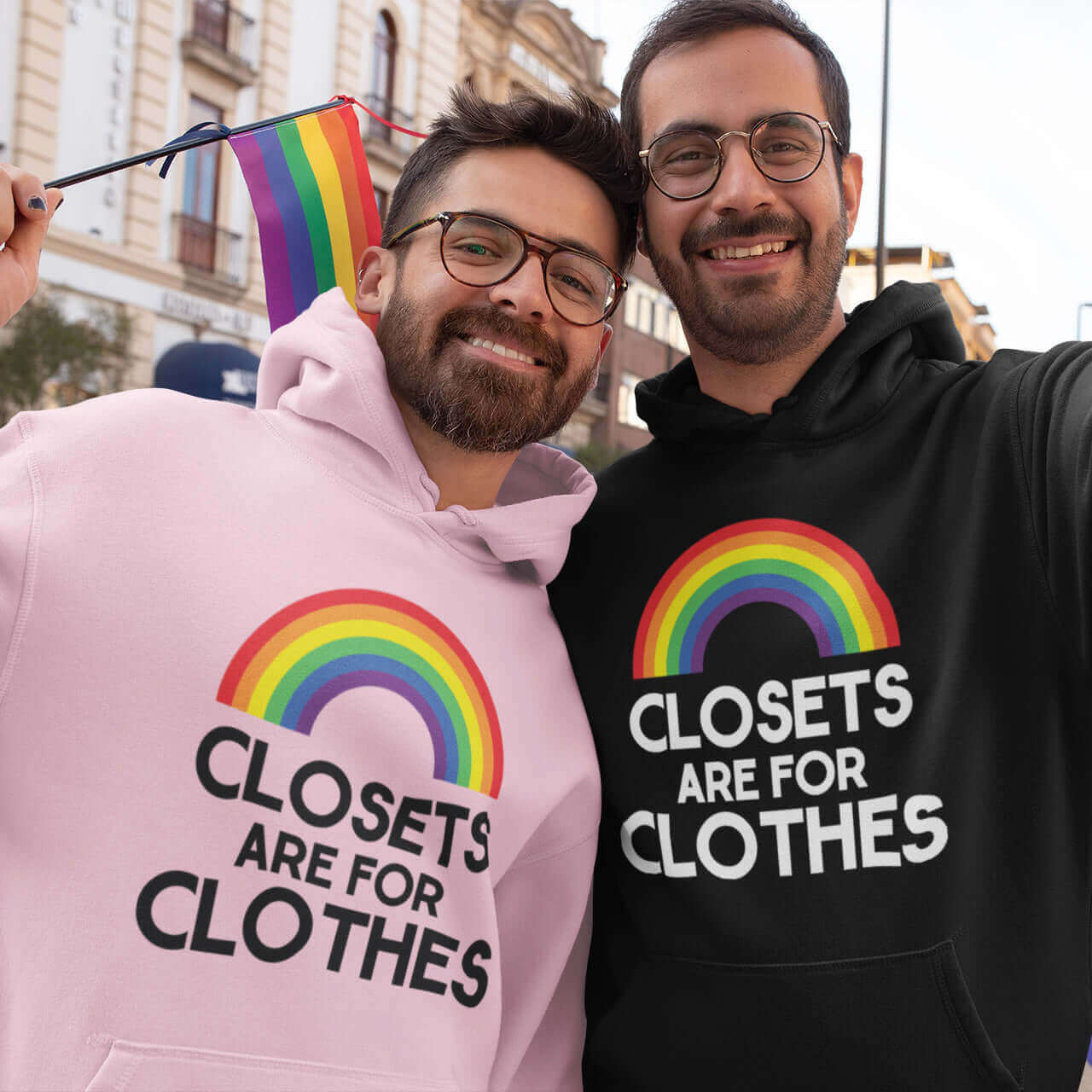 2 men at a pride event. They are both wearing hoodie sweatshirts with a rainbow and the words Clothes are for closets printed on the front.