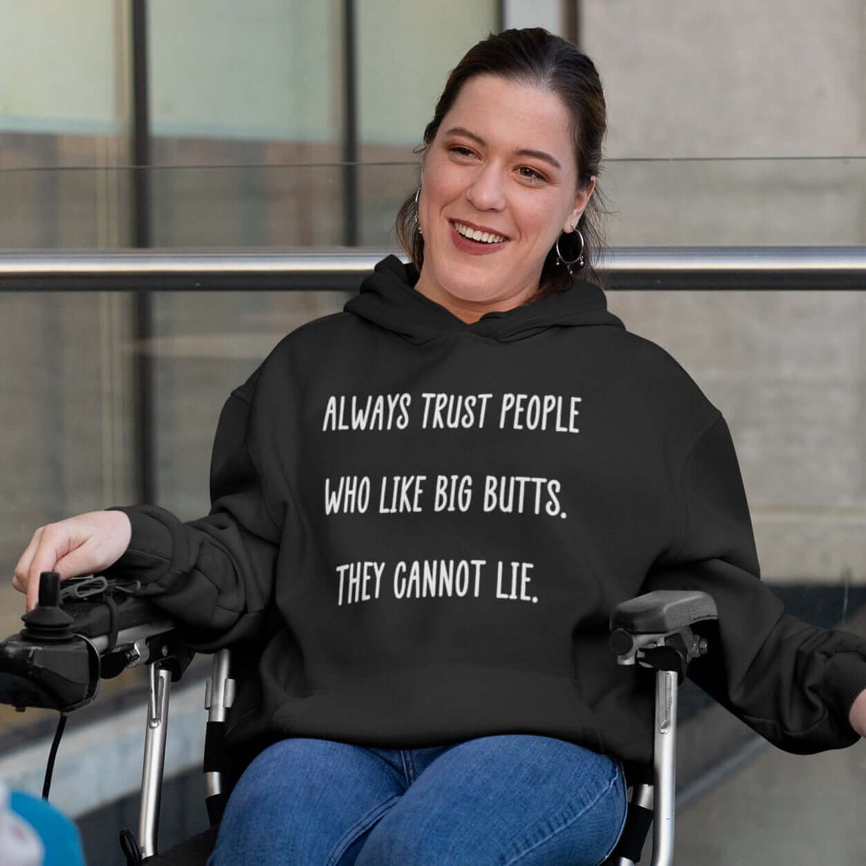 Woman in a wheelchair wearing a black hoodie sweatshirt with the funny phrase Always trust people who like big butts, they can not lie printed on the front.