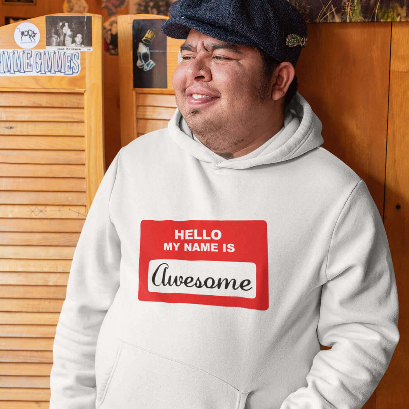 Man wearing a white hoodie sweatshirt with an image of a classic red and white sticker name tag that says Hello my name is Awesome printed on the front.