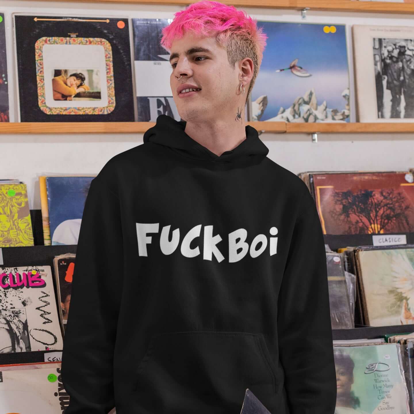 Man with pink hair wearing a black hoodie sweatshirt with the word Fuckboi printed on the front.