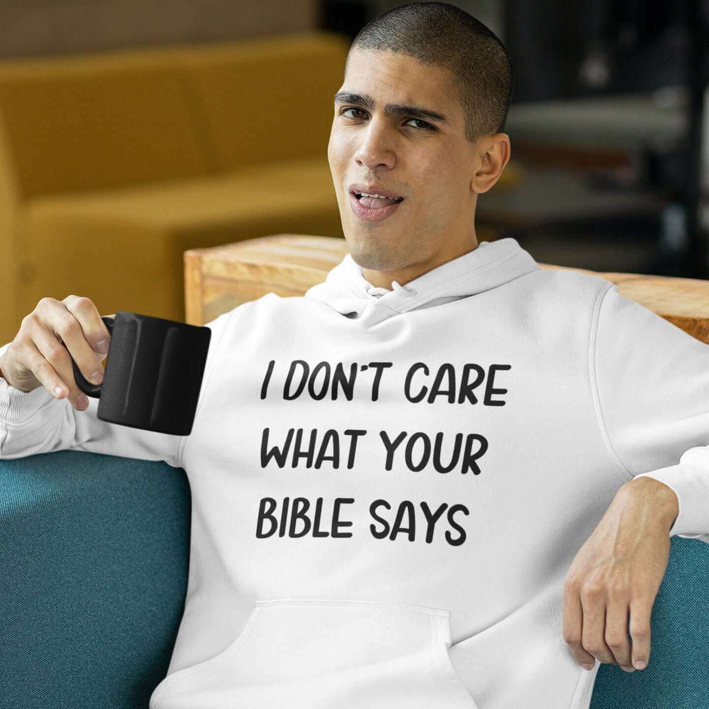 Man with sassy look on his face wearing a white hoodie sweatshirt with the words I don't care what your bible says printed on the front.