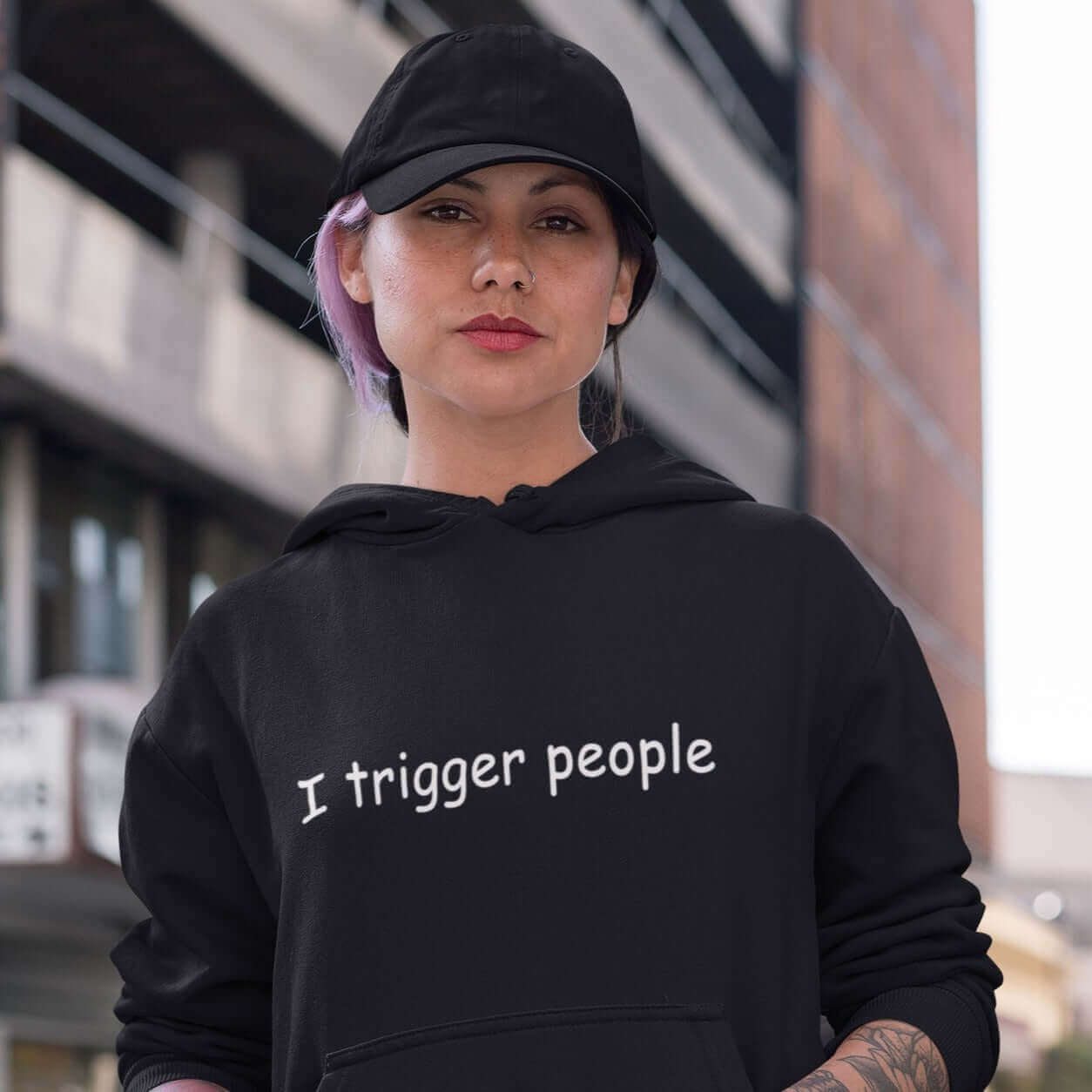 Woman wearing a black hoodie sweatshirt with the phrase I trigger people printed on the front.