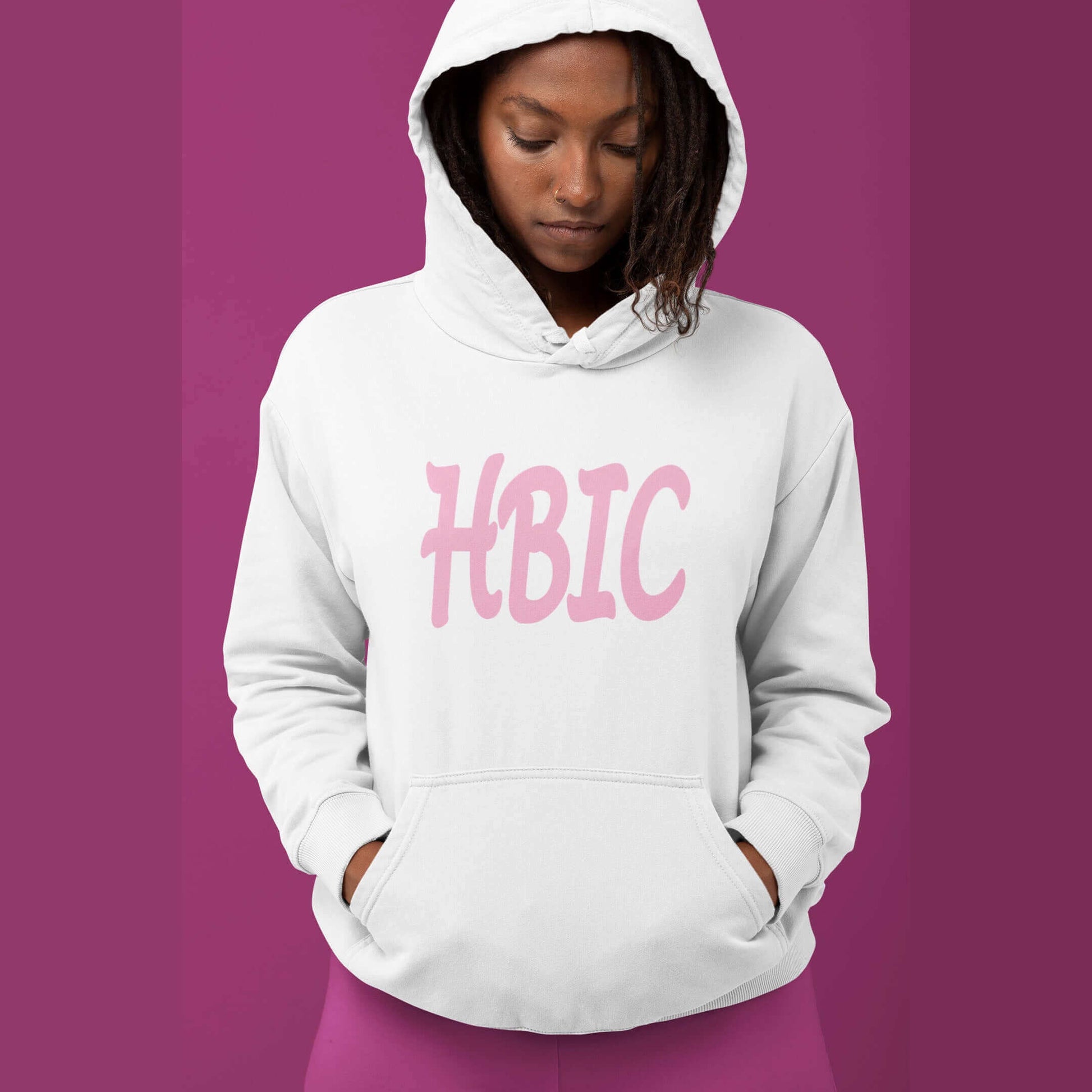 Woman wearing white hooded sweatshirt with the acronym HBIC printed on the front in pink text.