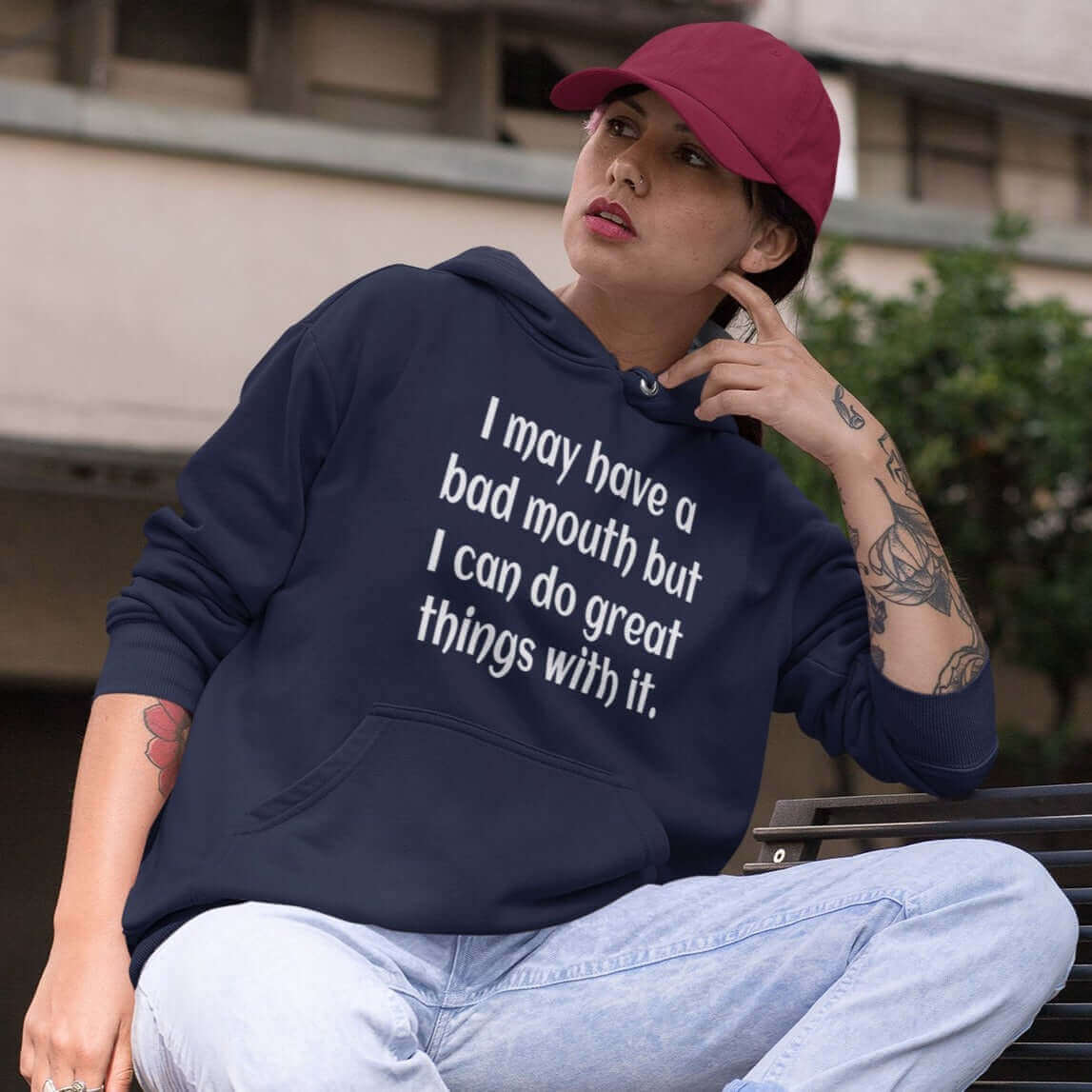 Woman wearing a navy blue hoodie sweatshirt with the phrase I may have a bad mouth but I can do great things with it printed on the front.