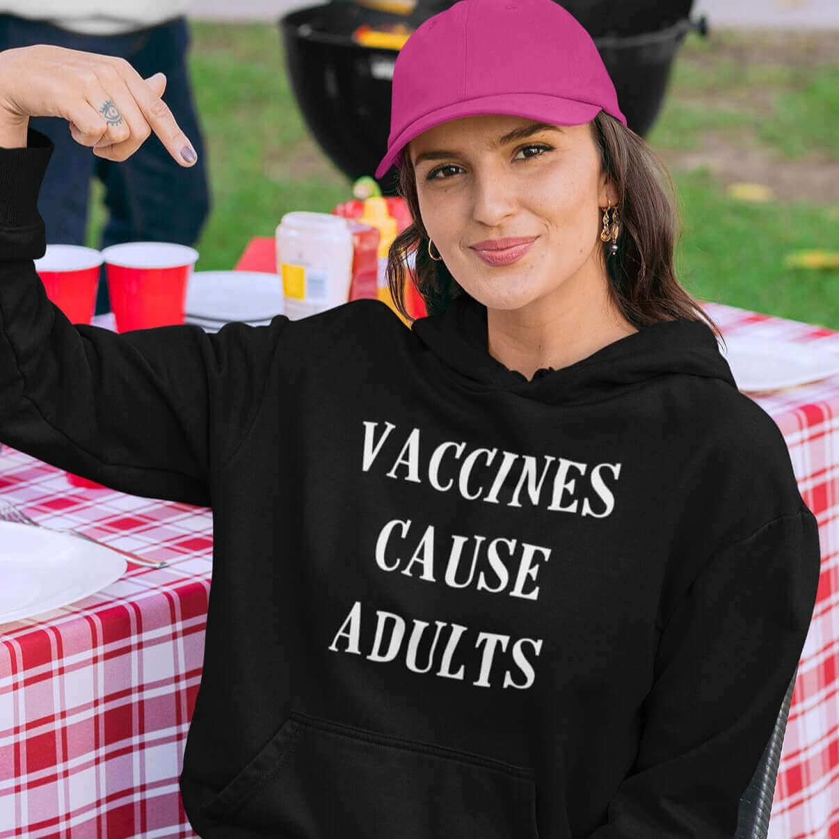 Woman wearing black hoodie sweatshirt with the words Vaccines cause adults printed on the front.