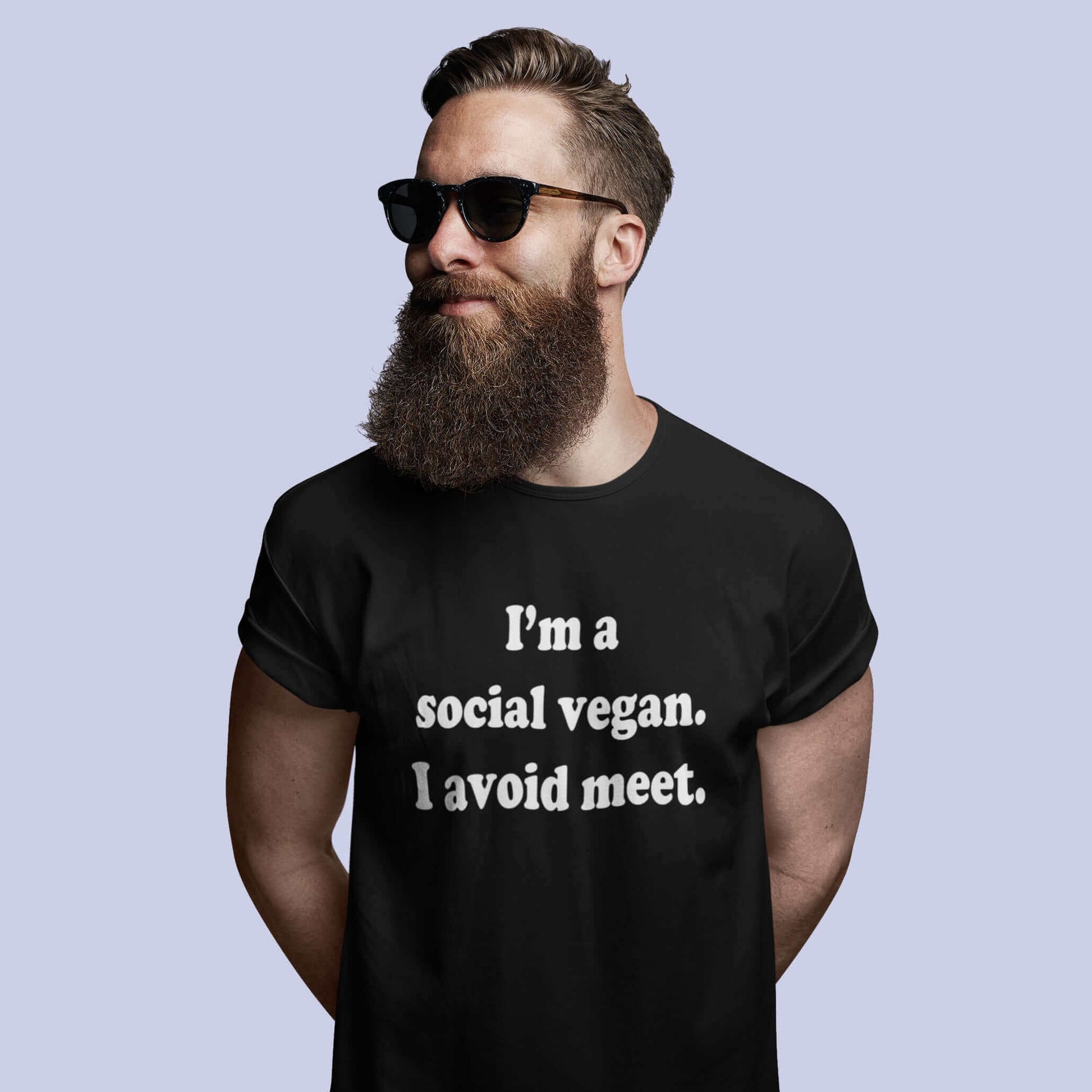 Bearded man wearing sunglasses and a black t-shirt with the pun phrase I'm a social vegan, I avoid meet printed on the front.