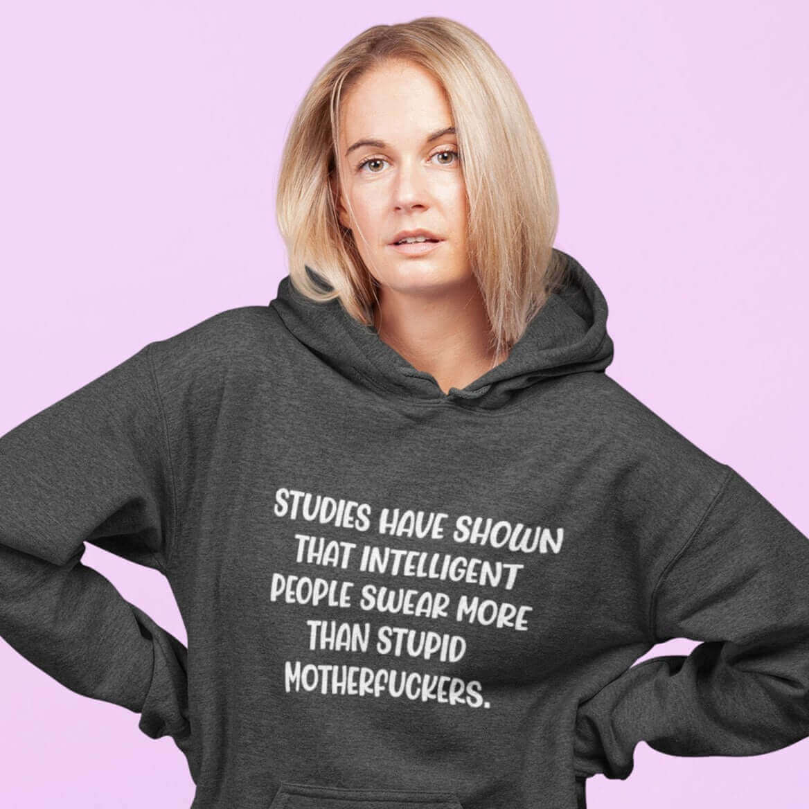 Woman wearing dark grey hoodie sweatshirt with the funny phrase Studies have shown that intelligent people swear more than stupid motherfuckers printed on the front.