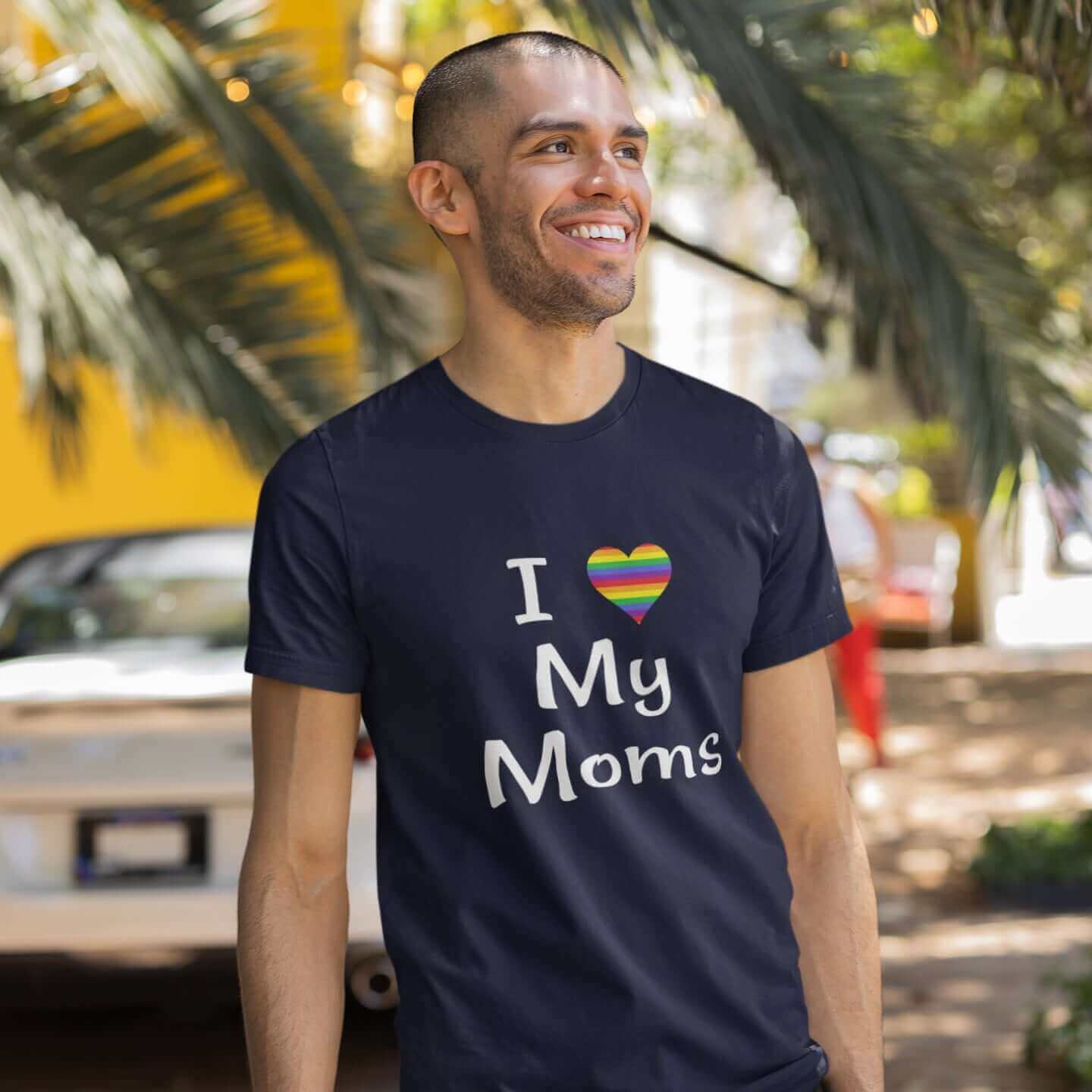 Man wearing navy blue t-shirt with I heart my moms printed on the front. The heart is rainbow colors.