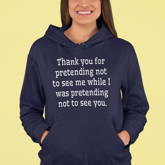 Woman wearing a navy blue hoodie sweatshirt with the social anxiety phrase Thank you for pretending not to see me while I was pretending not to see you printed on the front.