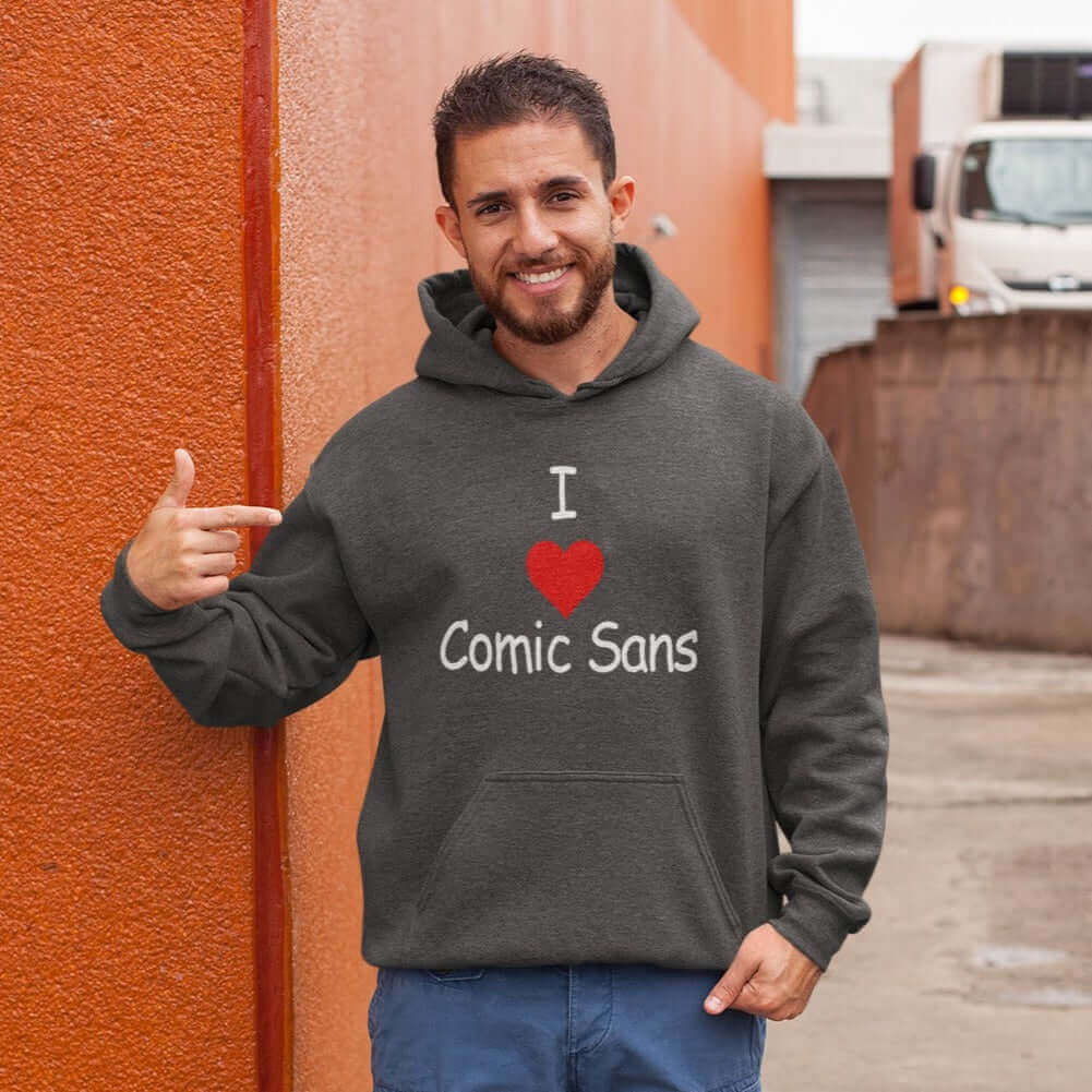 Man wearing dark heather grey hoodie sweatshirt with the phrase I heart Comic Sans on the front. The text is in comic sans font.