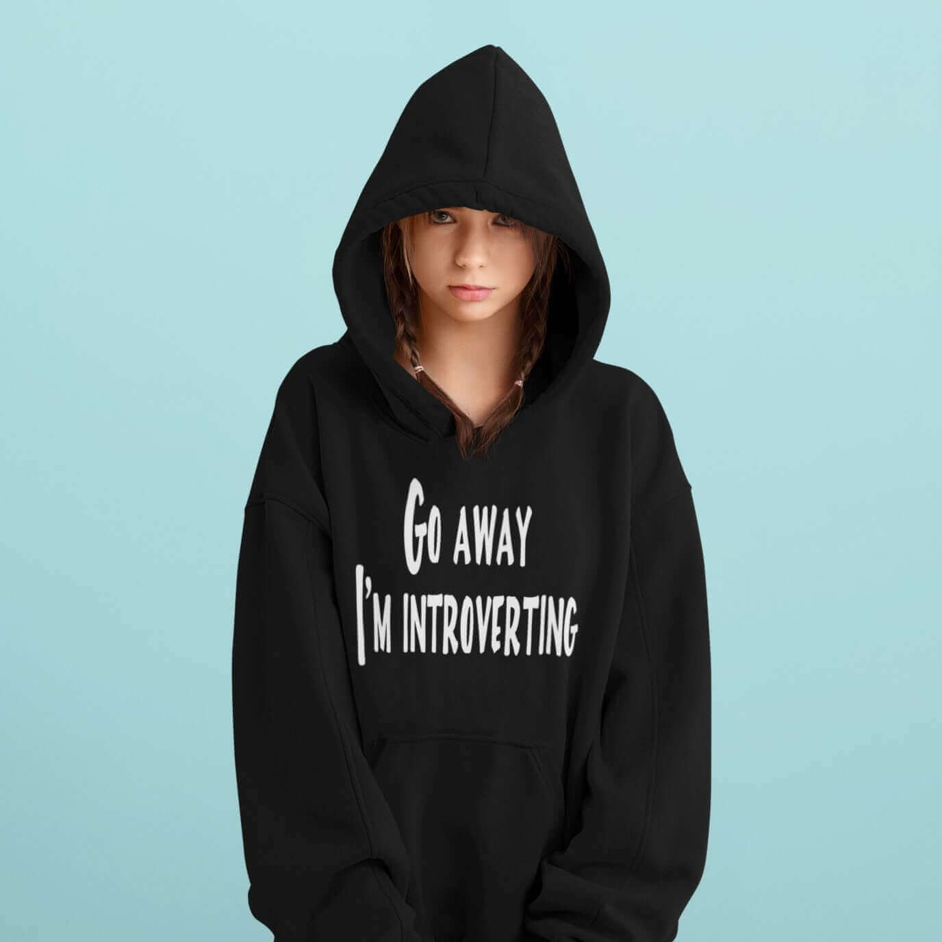 Woman wearing a black hoodie sweatshirt with the phrase Go away, I'm introverting printed on the front.