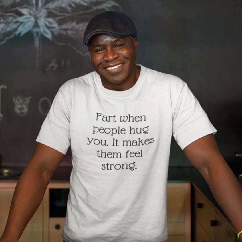 Man wearing a white t-shirt with the phrase Fart when people hug you. It makes them feel strong printed on the front.