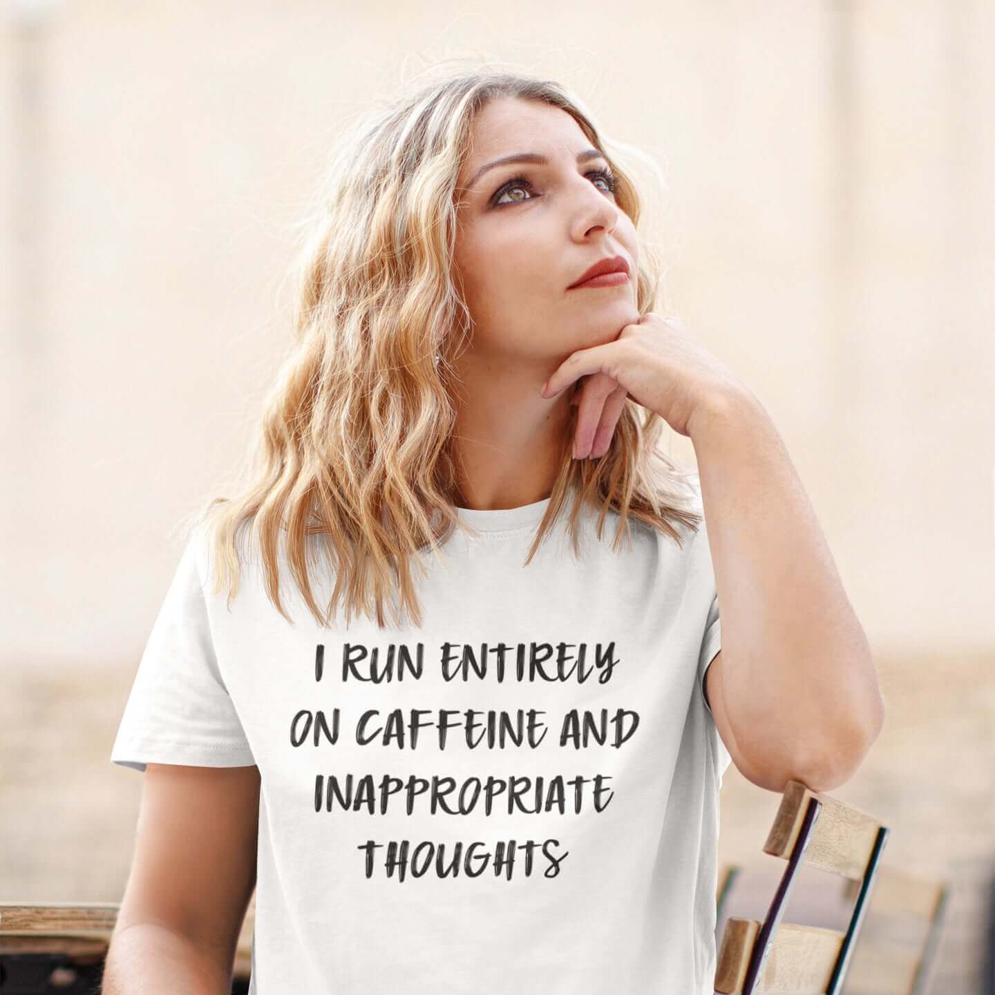 Woman wearing white t-shirt with the words I run entirely on caffeine & inappropriate thoughts printed on the front.
