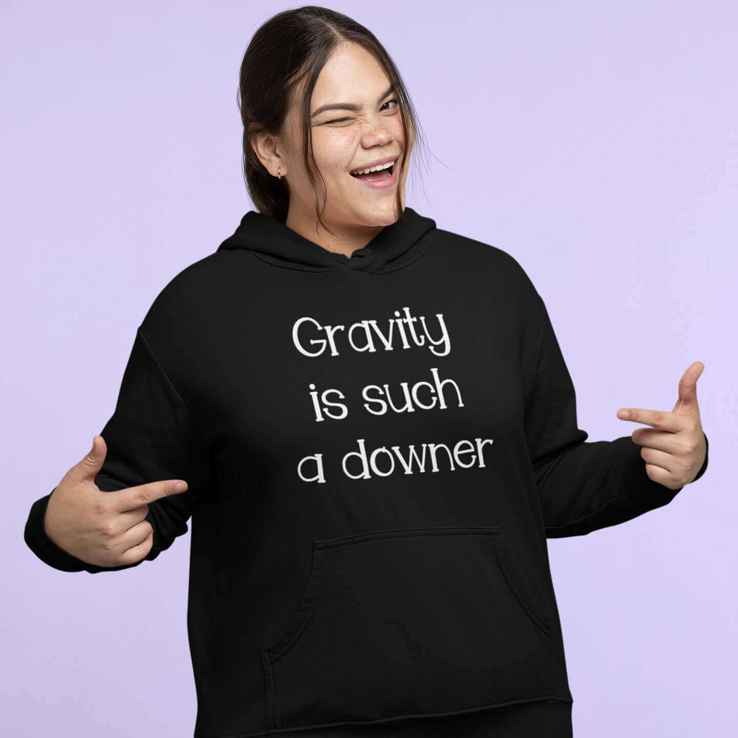 Woman wearing black hoodie sweatshirt with the words Gravity is such a downer printed on the front.