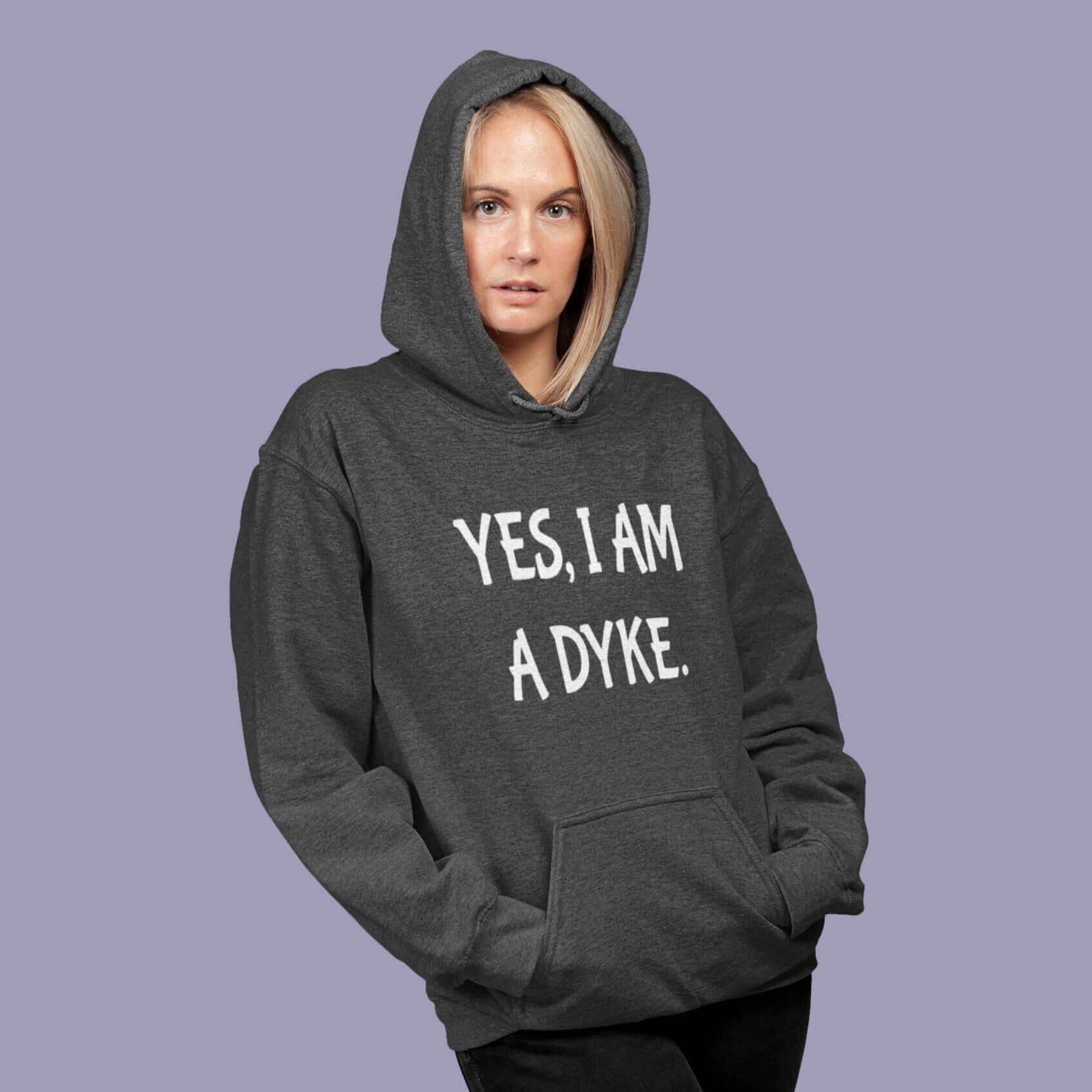 Woman wearing dark heather grey hoodie sweatshirt with the words Yes, I'm a dyke printed on the front.