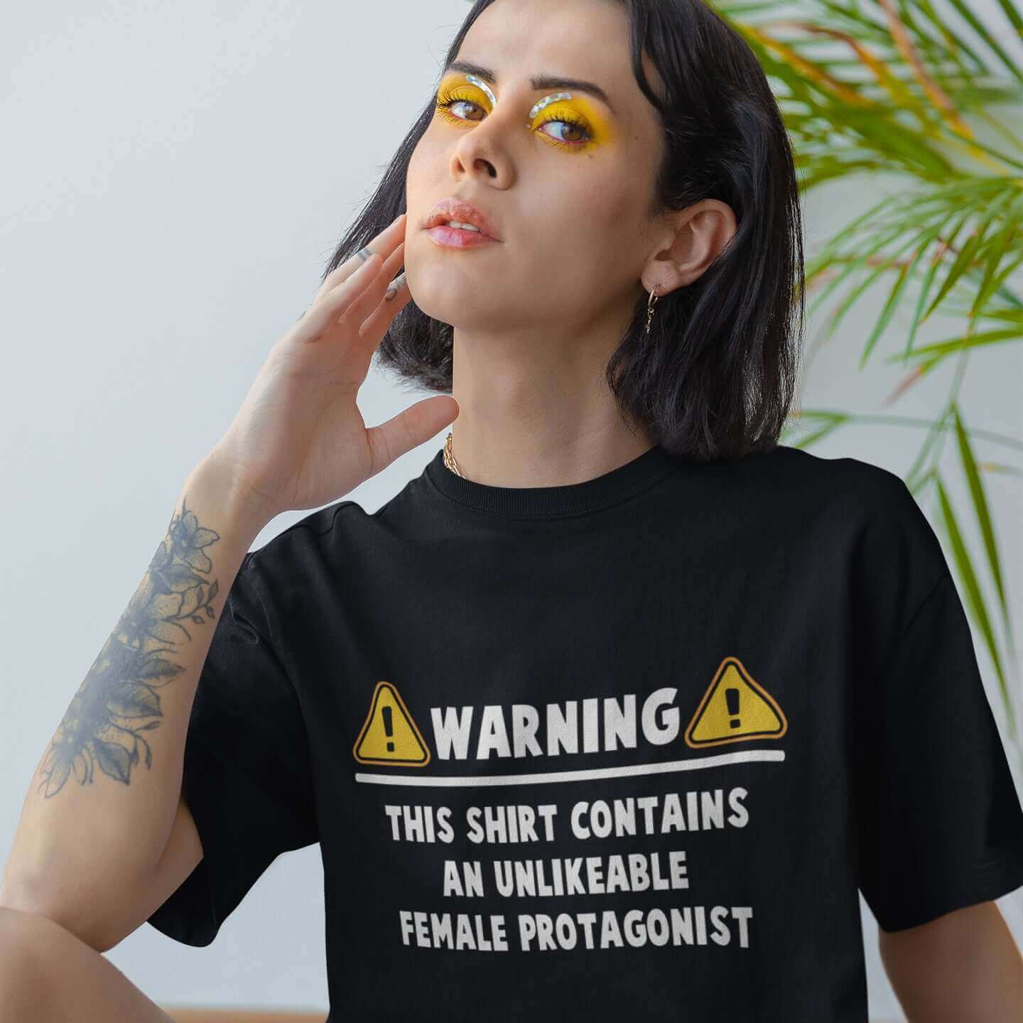 Woman wearing a black t-shirt with the words Warning this shirt contains an unlikable female protagonist printed on the front.