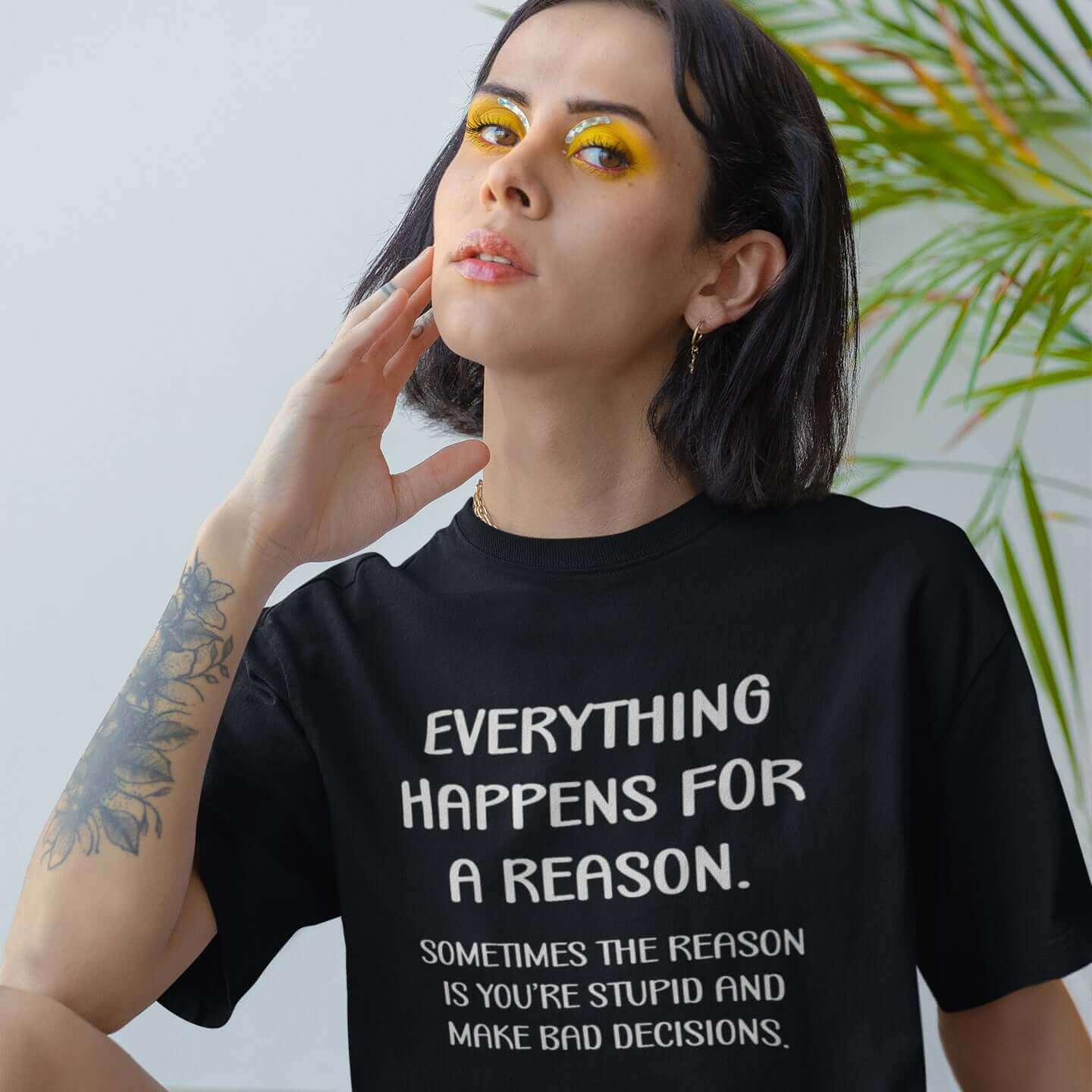 Serious woman wearing black t-shirt with the words Everything happens for a reason. Sometimes the reason is you're stupid and make bad decisions printed on the front.