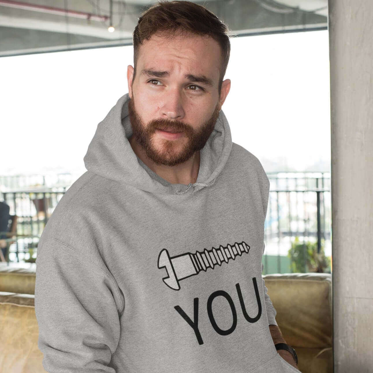 man wearing grey hoodie with screw you printed on front
