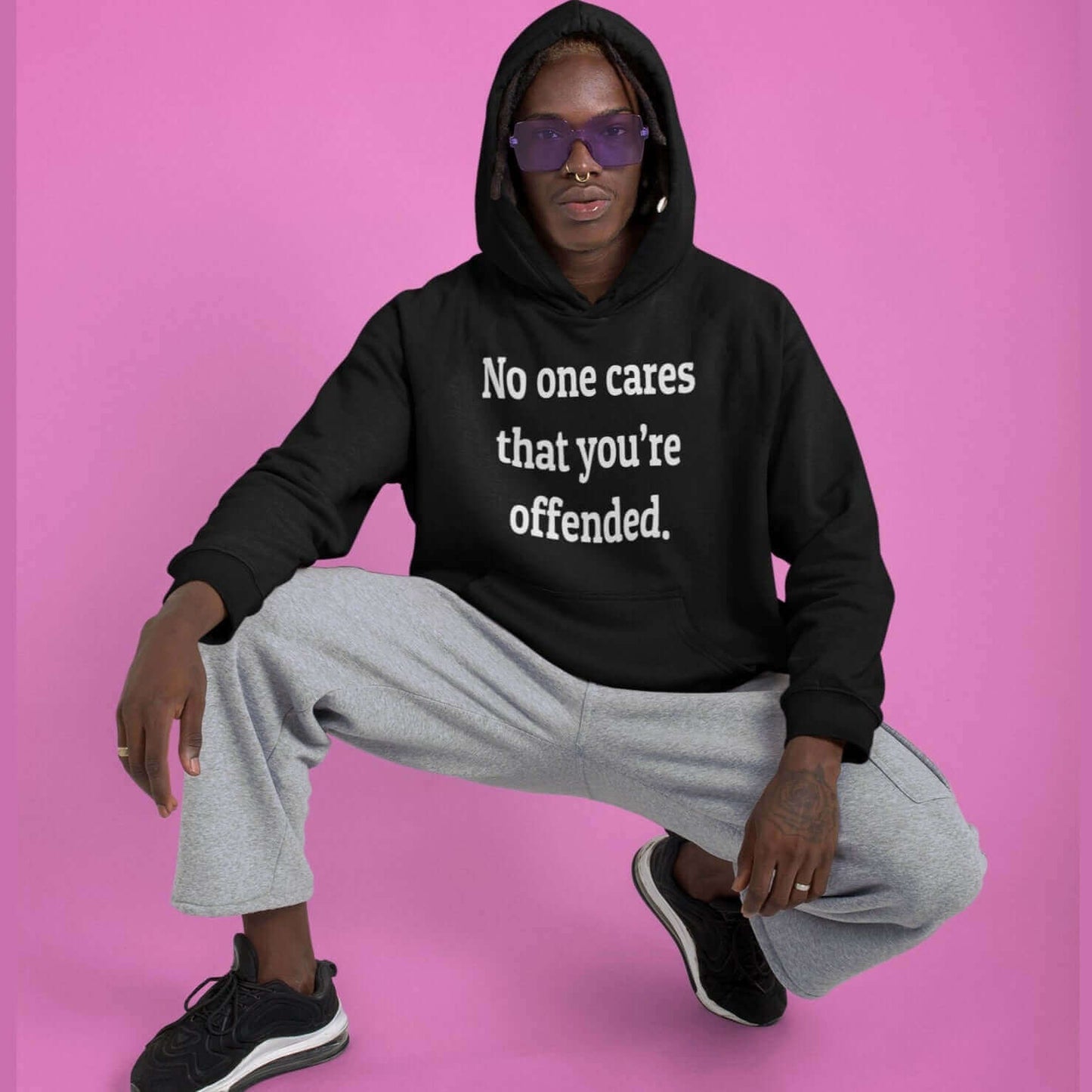 Man wearing black hoodie sweatshirt with the words No one cares that you're offended printed on the front.