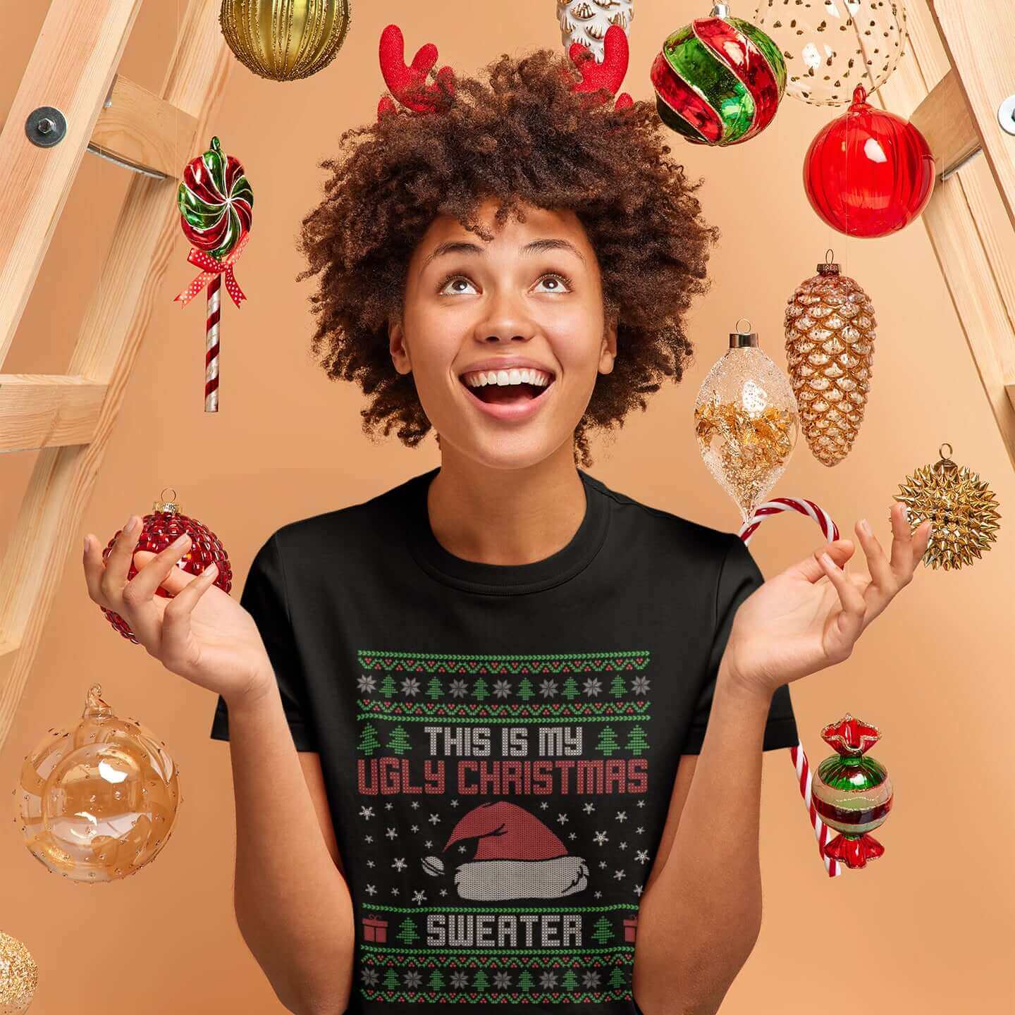 Woman in festive holiday setting wearing black t-shirt with the words This is my ugly Christmas sweater printed on the front. 