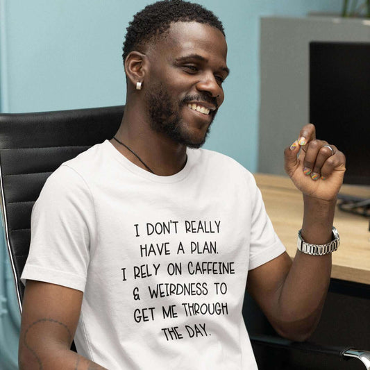 Smiling man wearing white t-shirt with the words I don't really have a plan. I rely on caffeine & weirdness to get me through the day printed on the front.