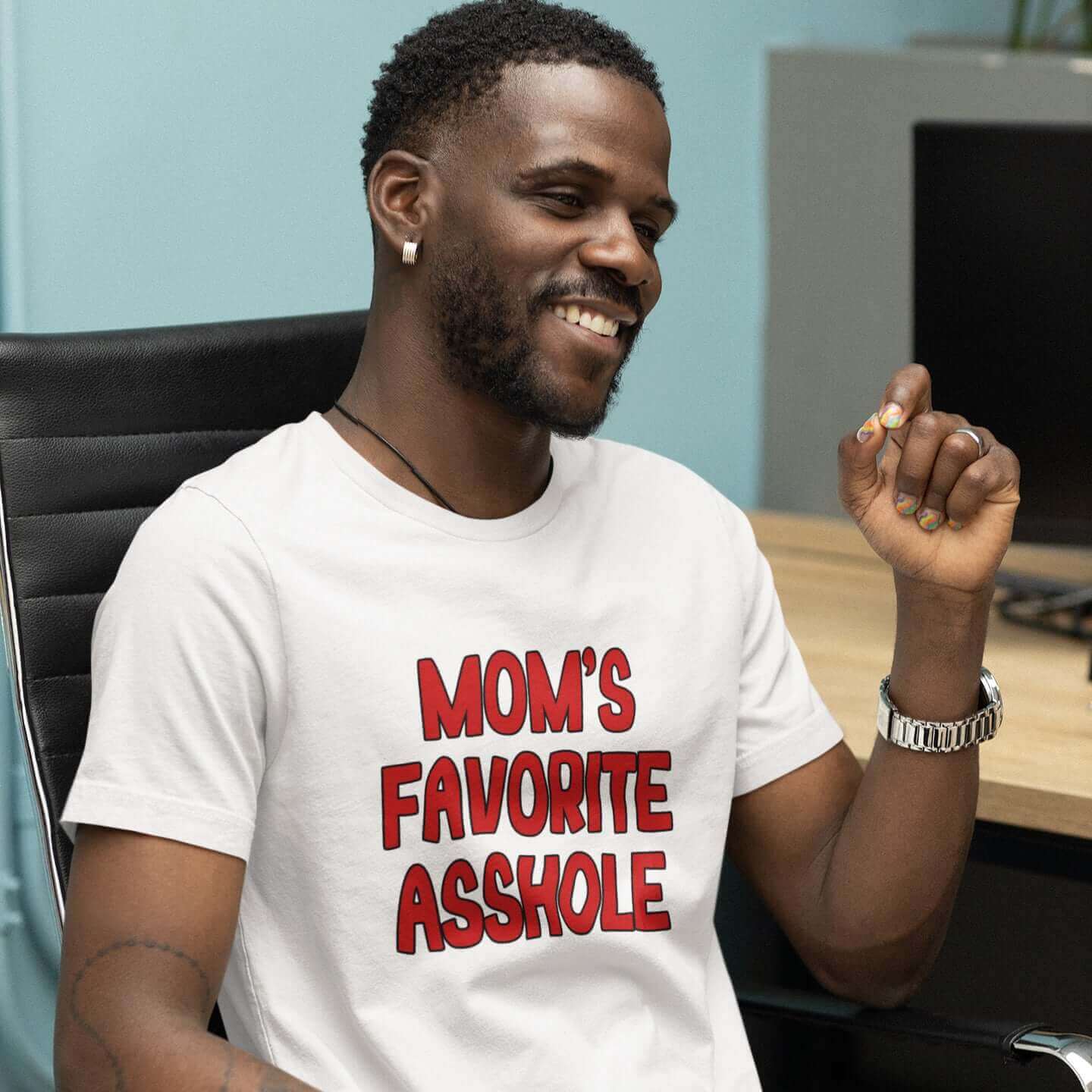 Smiling man wearing white t-shirt with the words Mom's favorite asshole printed in red on the front. 