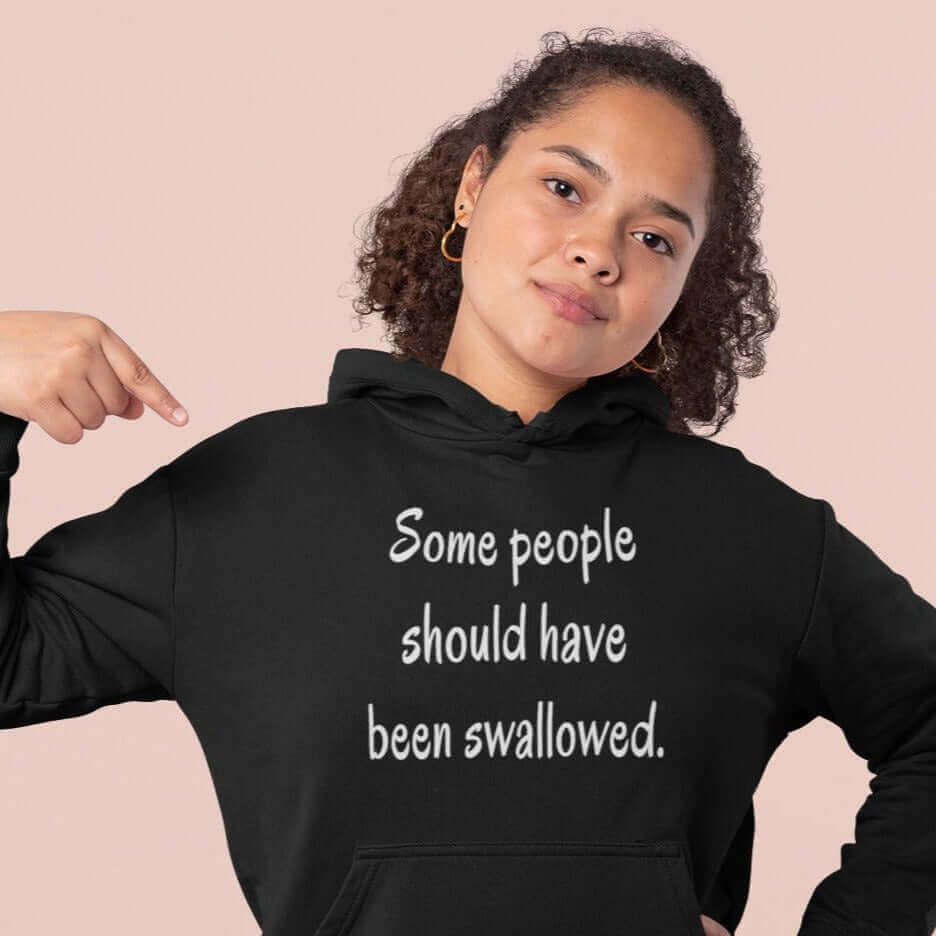 Woman wearing black hoodie sweatshirt with the phrase Some people should have been swallowed printed on the front.