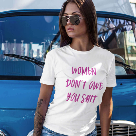 Woman wearing white t-shirt with the words Women don't owe you shit printed on the front in pink.