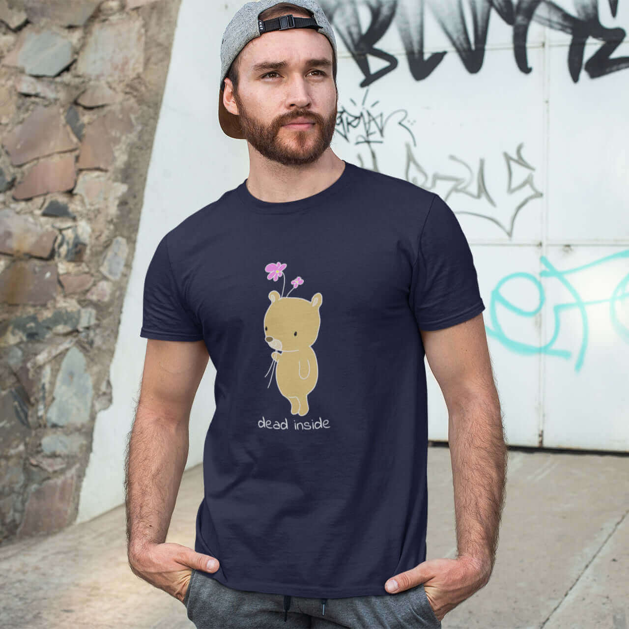 Man wearing navy blue t-shirt with an image of a cute bear holding 2 pink flowers. The words Dead inside are printed underneath the bear. The graphics are printed on the front of the shirt.