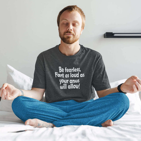 Man meditating while wearing a dark grey t-shirt with the phrase Be fearless. Fart as loud as your anus will allow printed on the front.