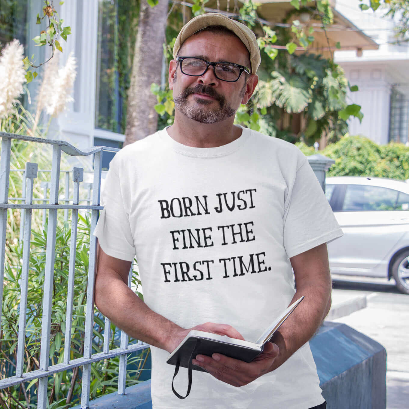 Man wearing white t-shirt with the words Born just fine the first time printed on the front.