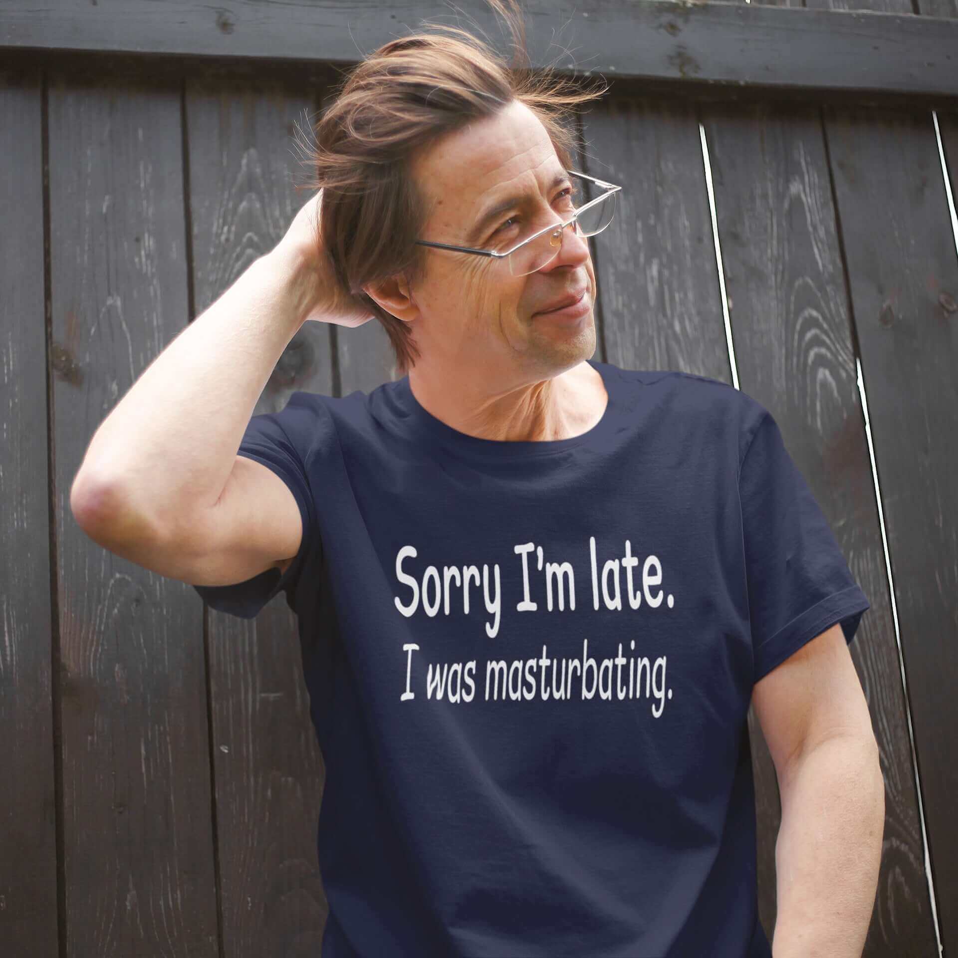 Man wearing a navy blue t-shirt with the phrase Sorry I'm late, I was masturbating printed on the front.