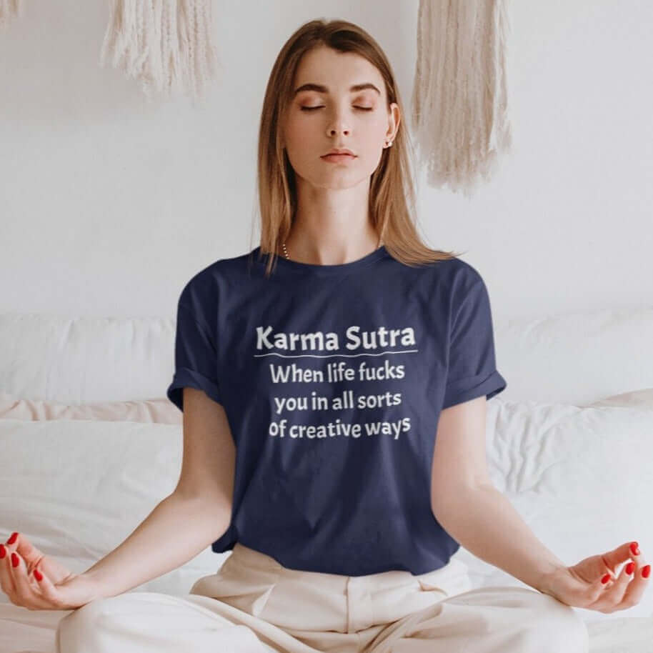 Woman meditating with her eyes closed while wearing a navy blue t-shirt with the funny phrase Karma sutra, when life fucks you in all sorts of creative ways printed on the front.