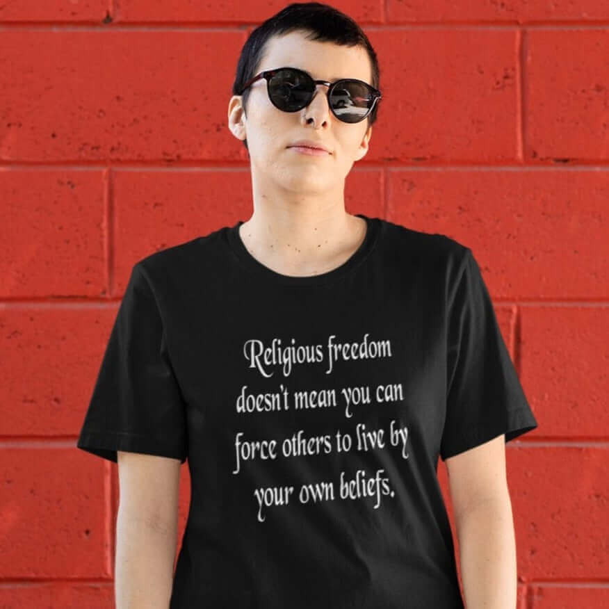 Woman wearing sunglasses and a black t-shirt with the phrase Religious freedom doesn't mean you can force others to live by your own beliefs printed on the front.