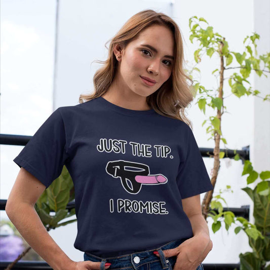 Woman wearing navy blue t-shirt that has an image of a strap-on dildo and the words Just the tip, I promise printed on the front. The graphics are pink, black and white.