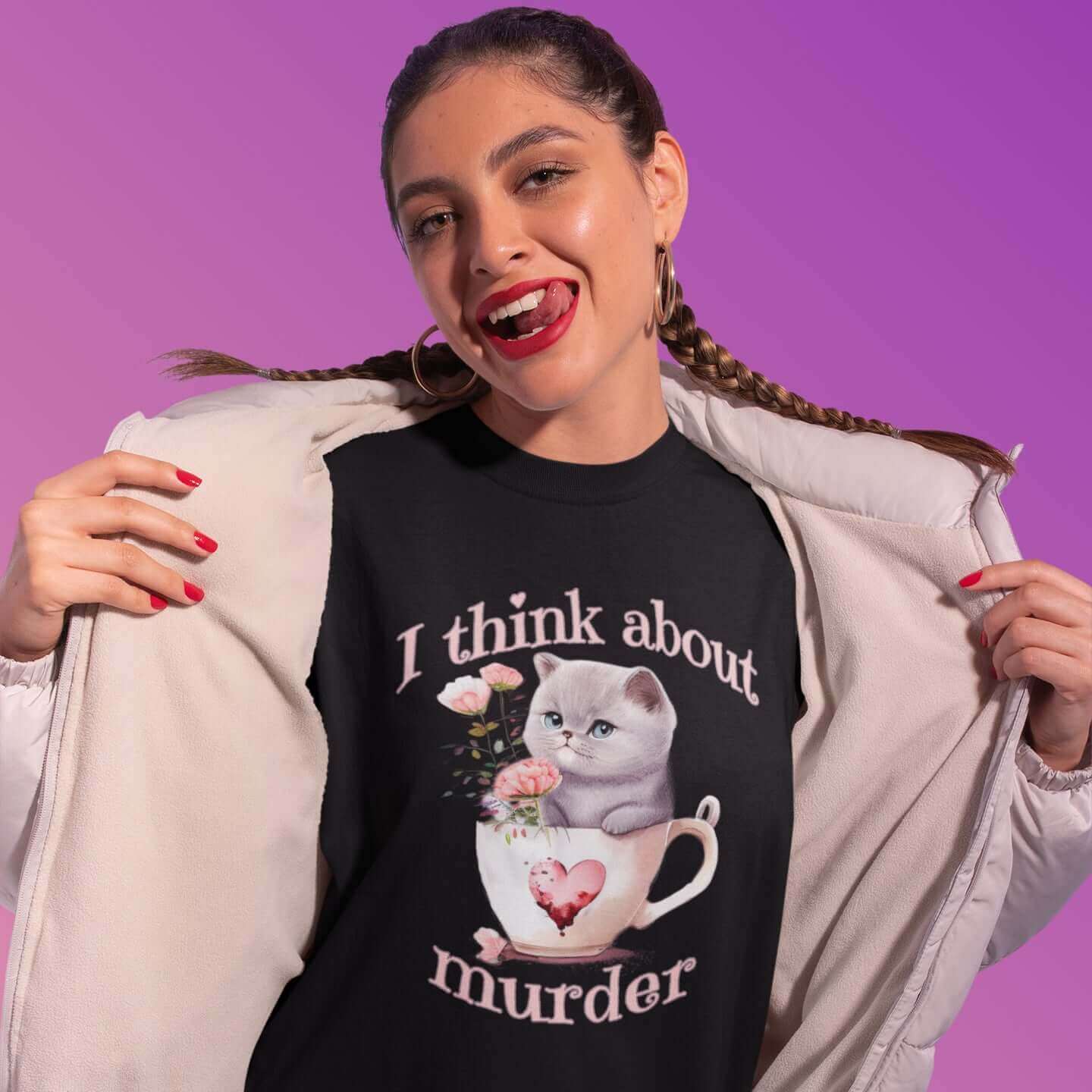 Woman wearing a black t-shirt that says I think about murder with image of cute fluffy kitten sitting in a teacup printed on the front.