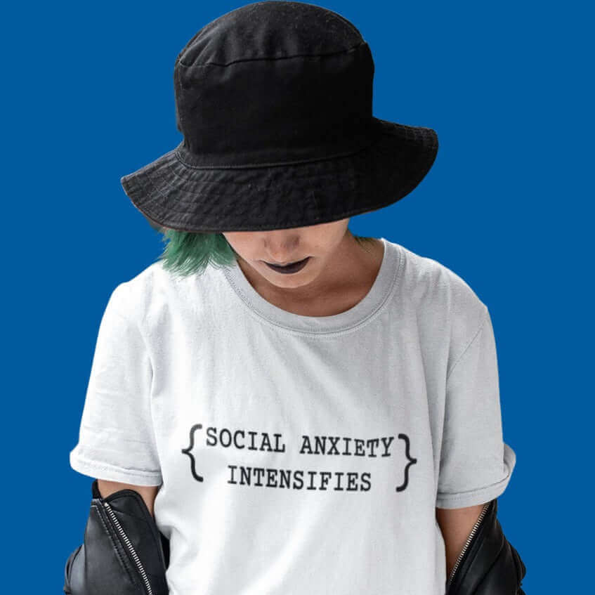 Bashful looking woman wearing white t-shirt with the words Social anxiety intensifies printed on the front.