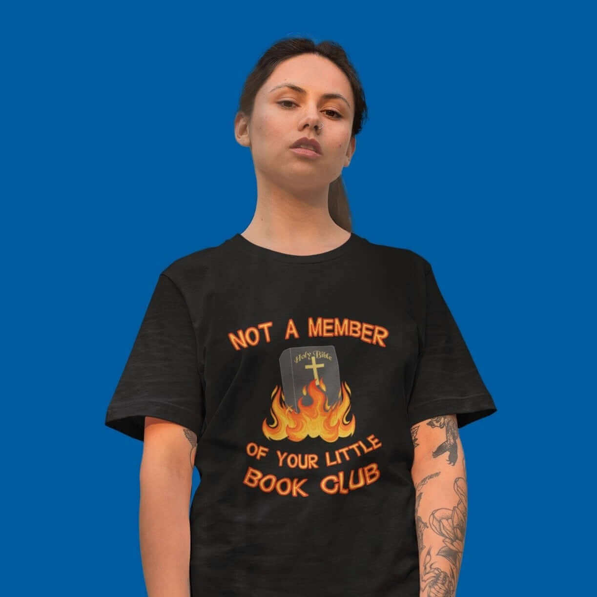 Woman wearing black t-shirt with image of a burning bible and the words Not a member of your little book club printed on the front.