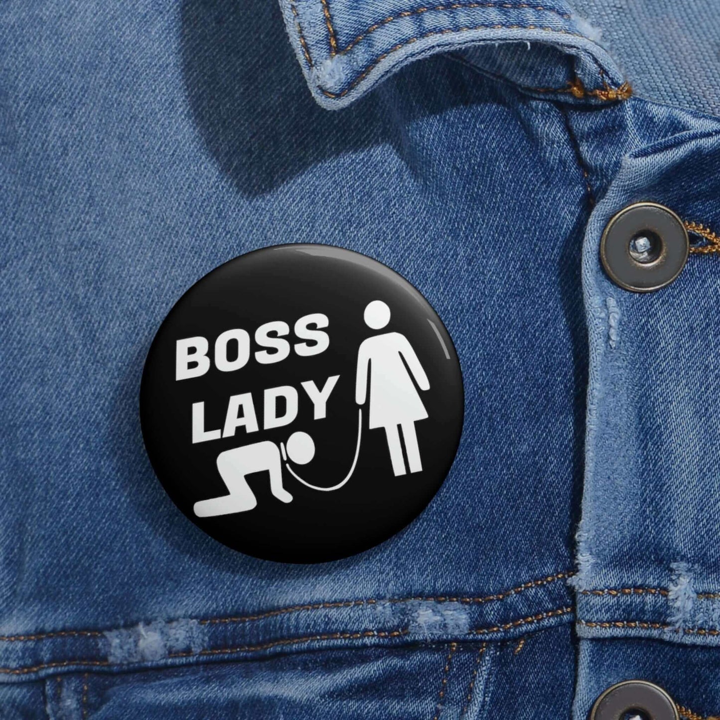 Black pinback button with graphic of collared and leashed man on his hands and knees being led by a woman and the words Boss lady.