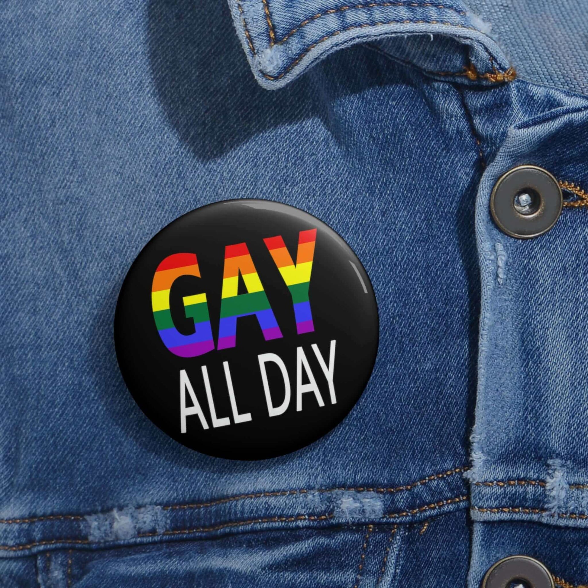 Black pin-back button that says Gay all day in rainbow font.