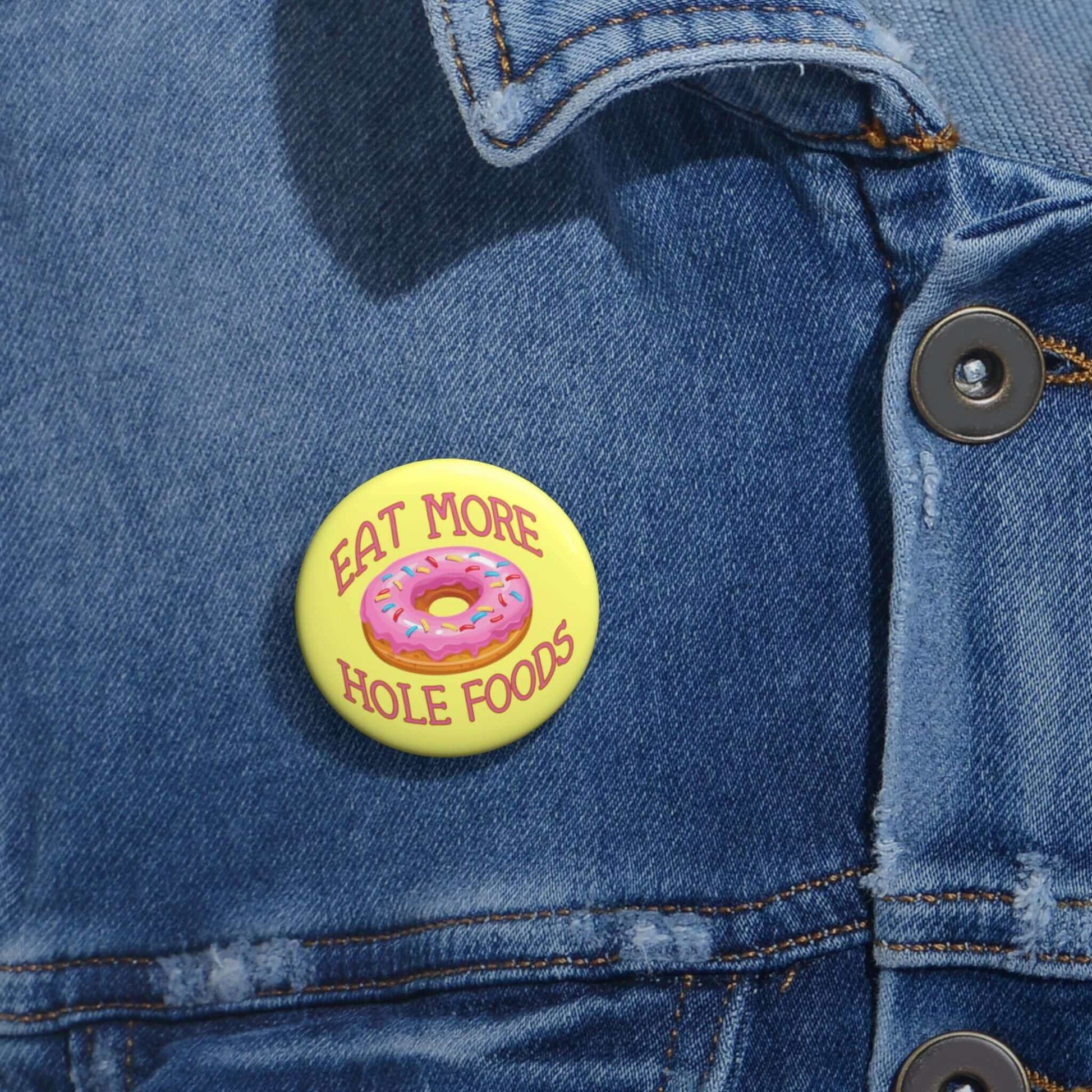 Funny donut pun pinback button with image of a donut with pink icing and sprinkles with the words Eat more hole foods.
