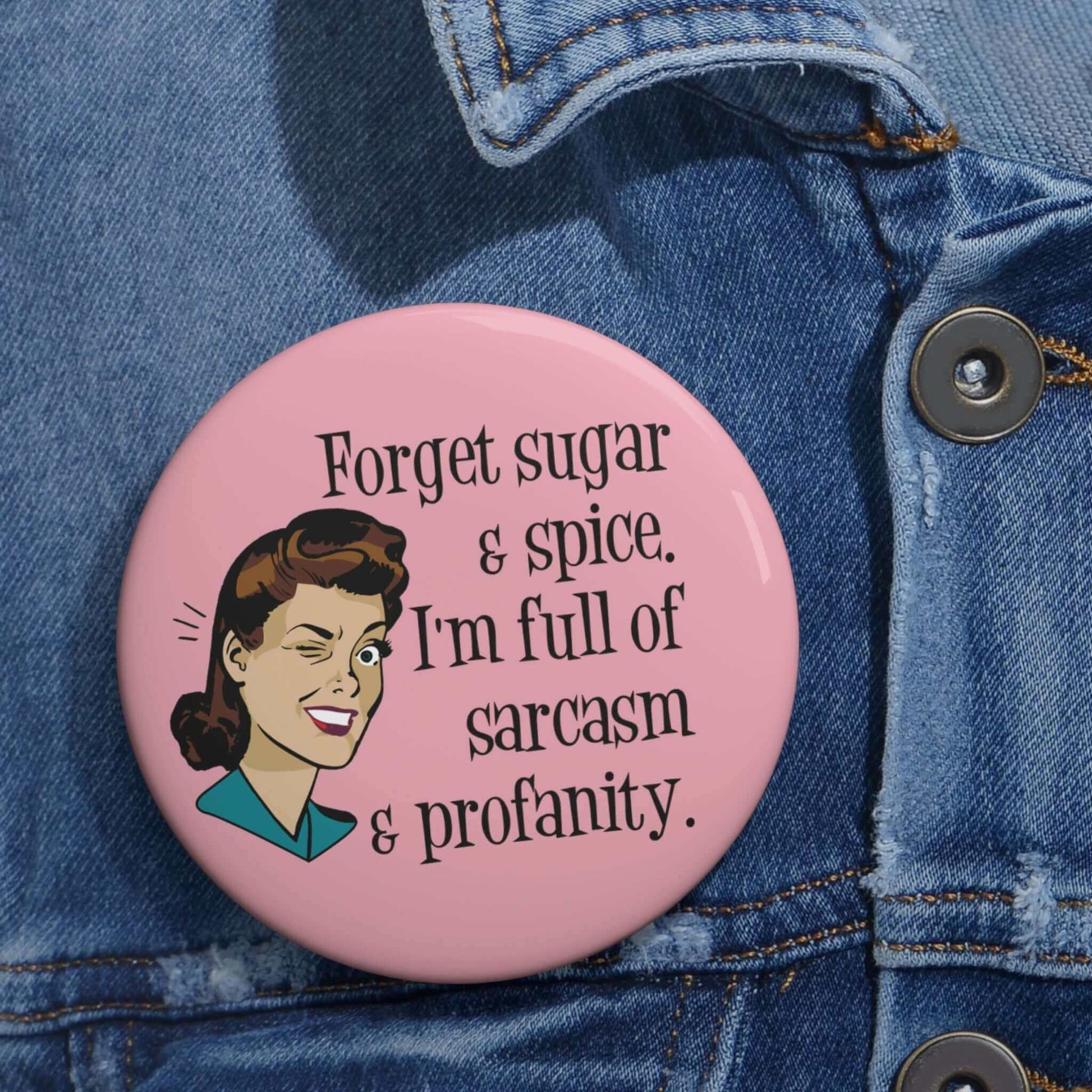 Pink pin-back button with image of winking retro woman and the words Forget sugar and spice, I'm full of sarcasm and profanity.